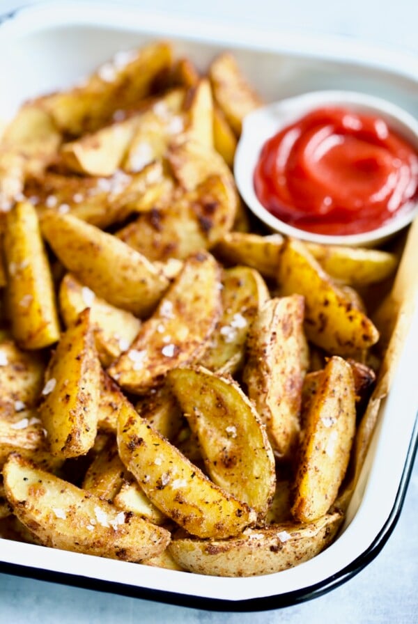 Perfect Roasted Potato Wedges with ketchup in white enamel tray.