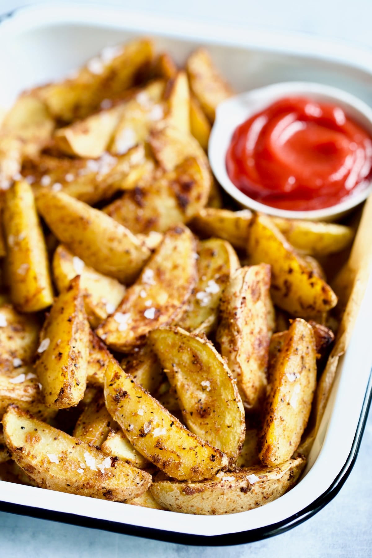 Perfect Roasted Potato Wedges with ketchup in white enamel tray.