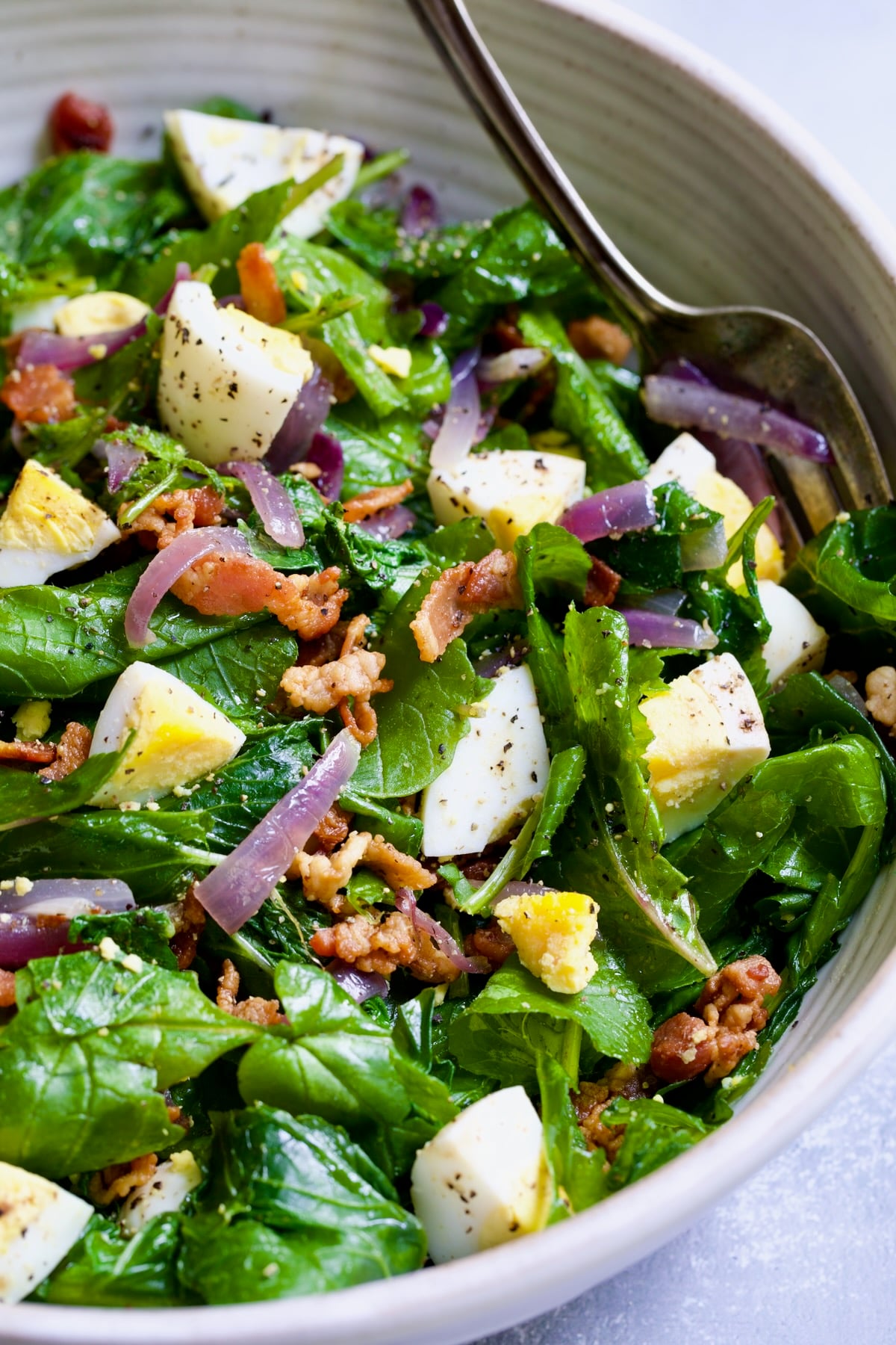 Radish Greens Salad with Hot Bacon Dressing in white serving bowl.