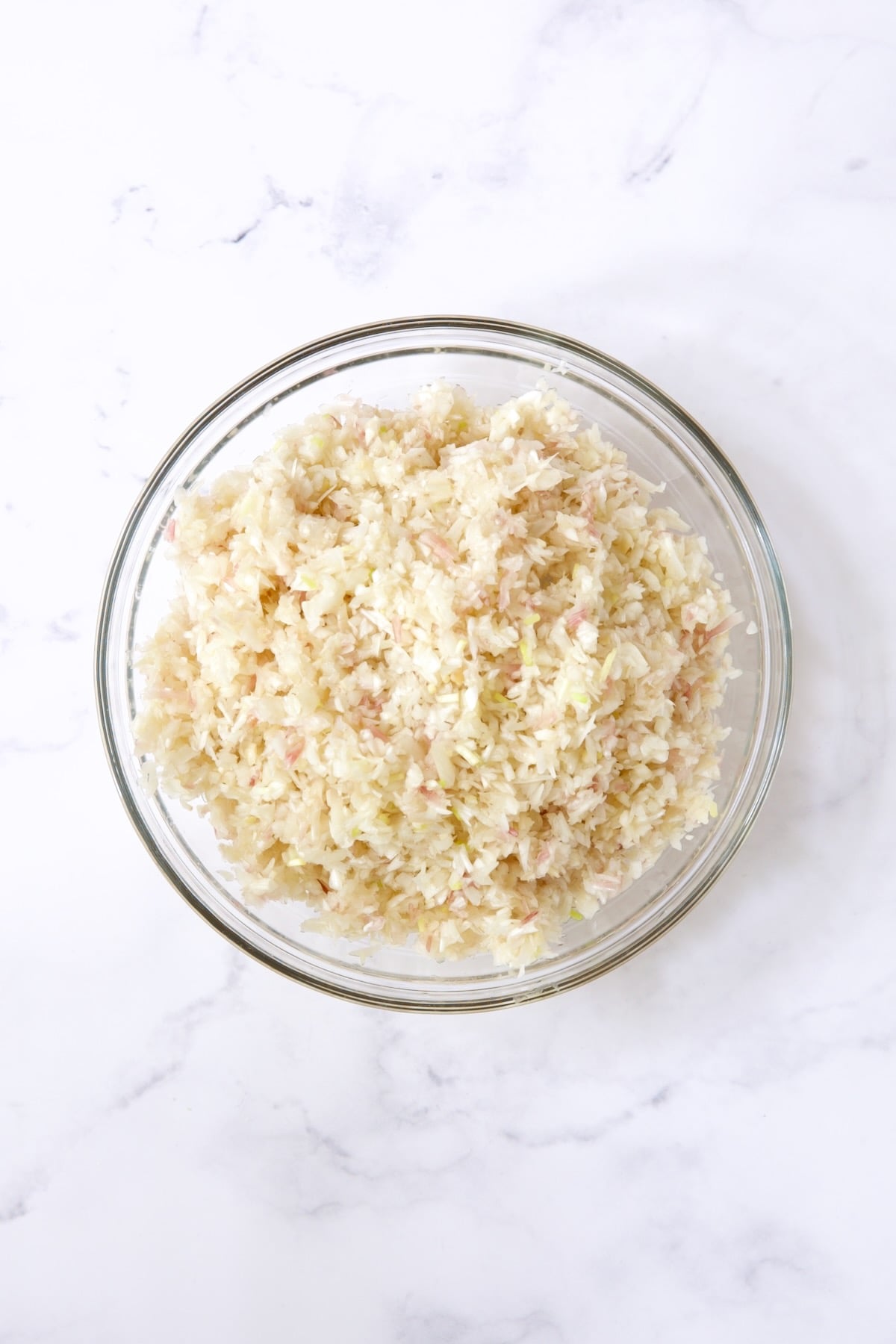 Finely chopped ramps in glass bowl.
