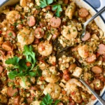 Low-Carb Jambalaya with Chicken Shrimp and Sausage with serving utensils garnished with fresh parsley.