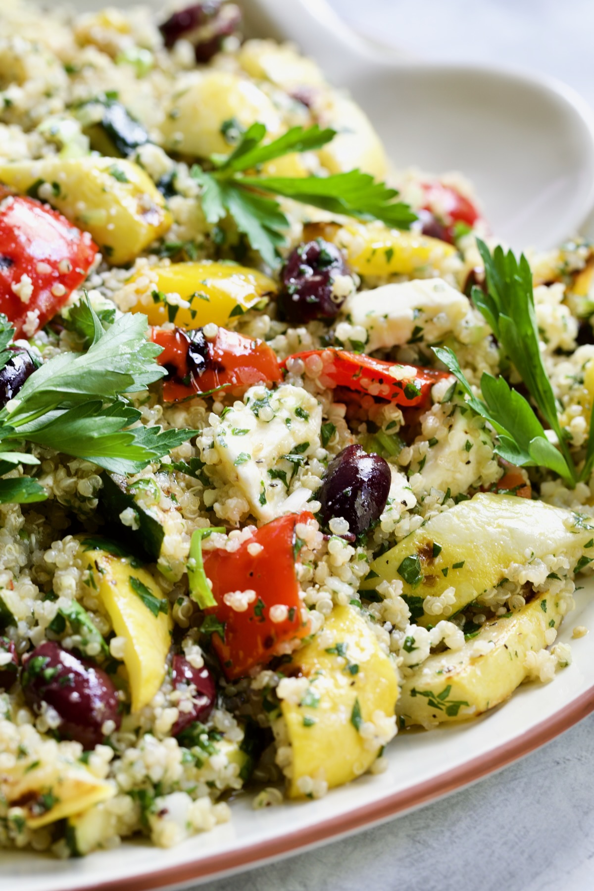 Mediterranean Quinoa Salad with Grilled Vegetables on platter with serving spoon.