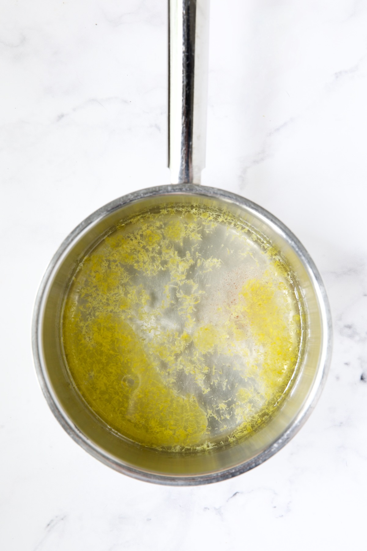 Water and lemon zest in stainless steel saucepan.