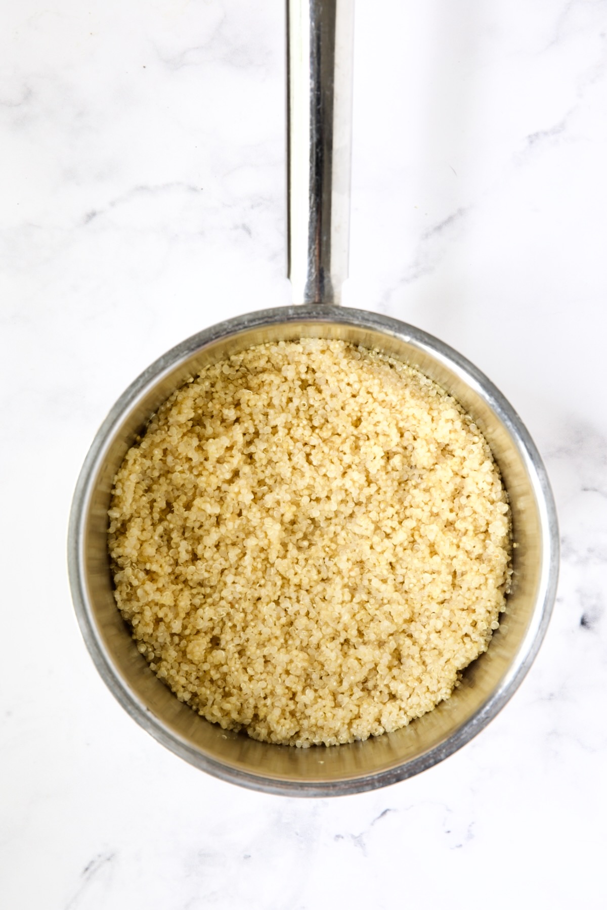 Cooked quinoa in stainless steel saucepan.