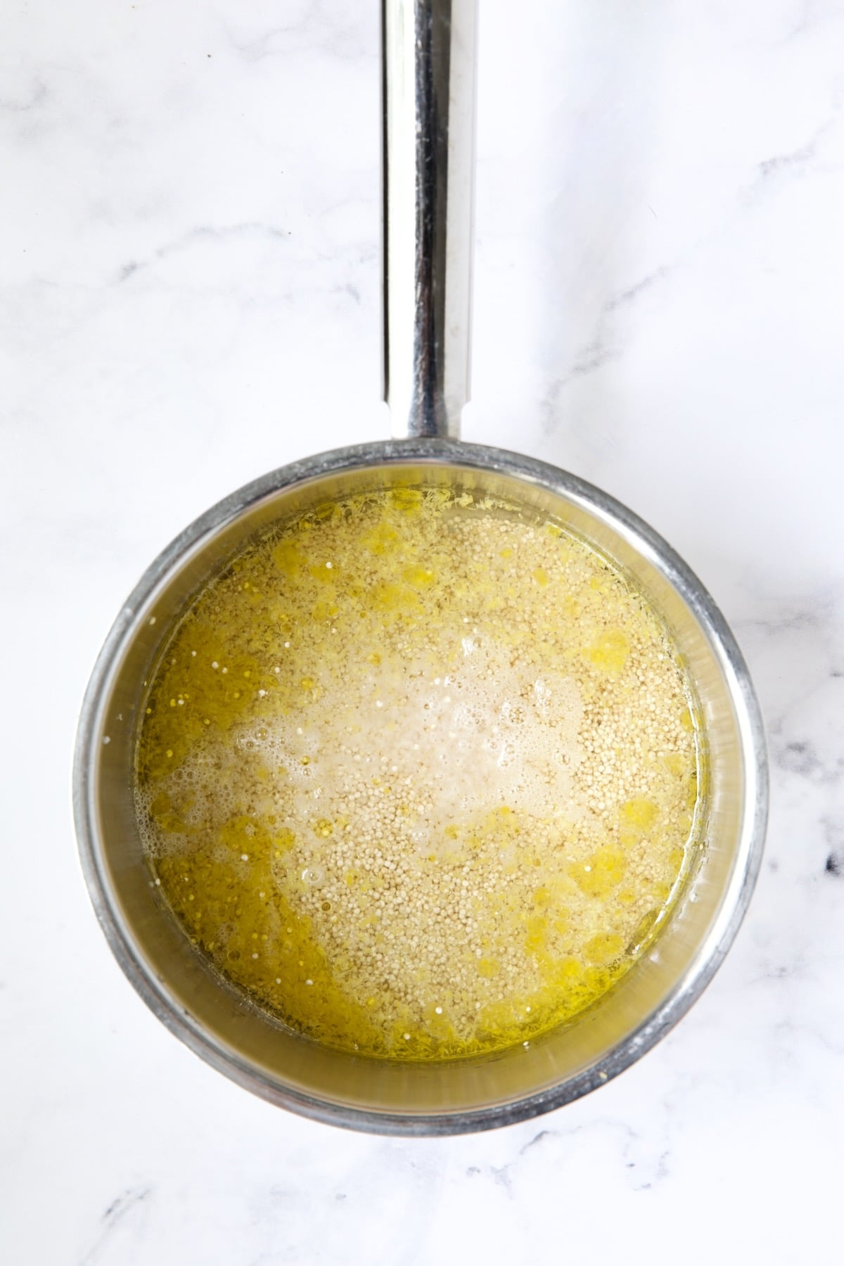 Water, lemon zest and quinoa in stainless steel saucepan.