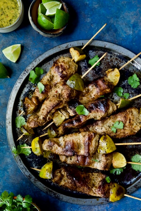Mojo-Marinated Pork Skewers on metal tray garnished with cilantro.
