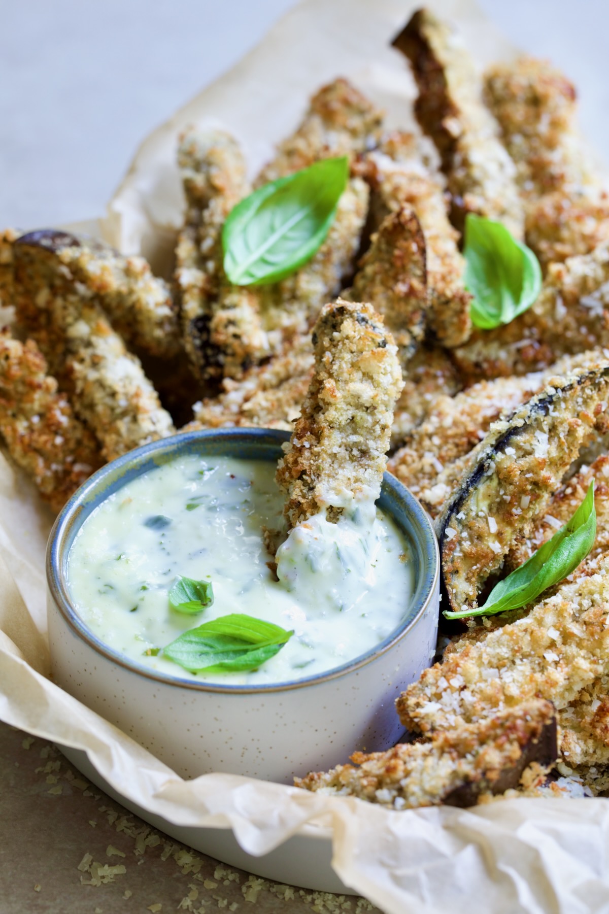 Eggplant fries in basket with one dipped into Garlic Basil Aioli.