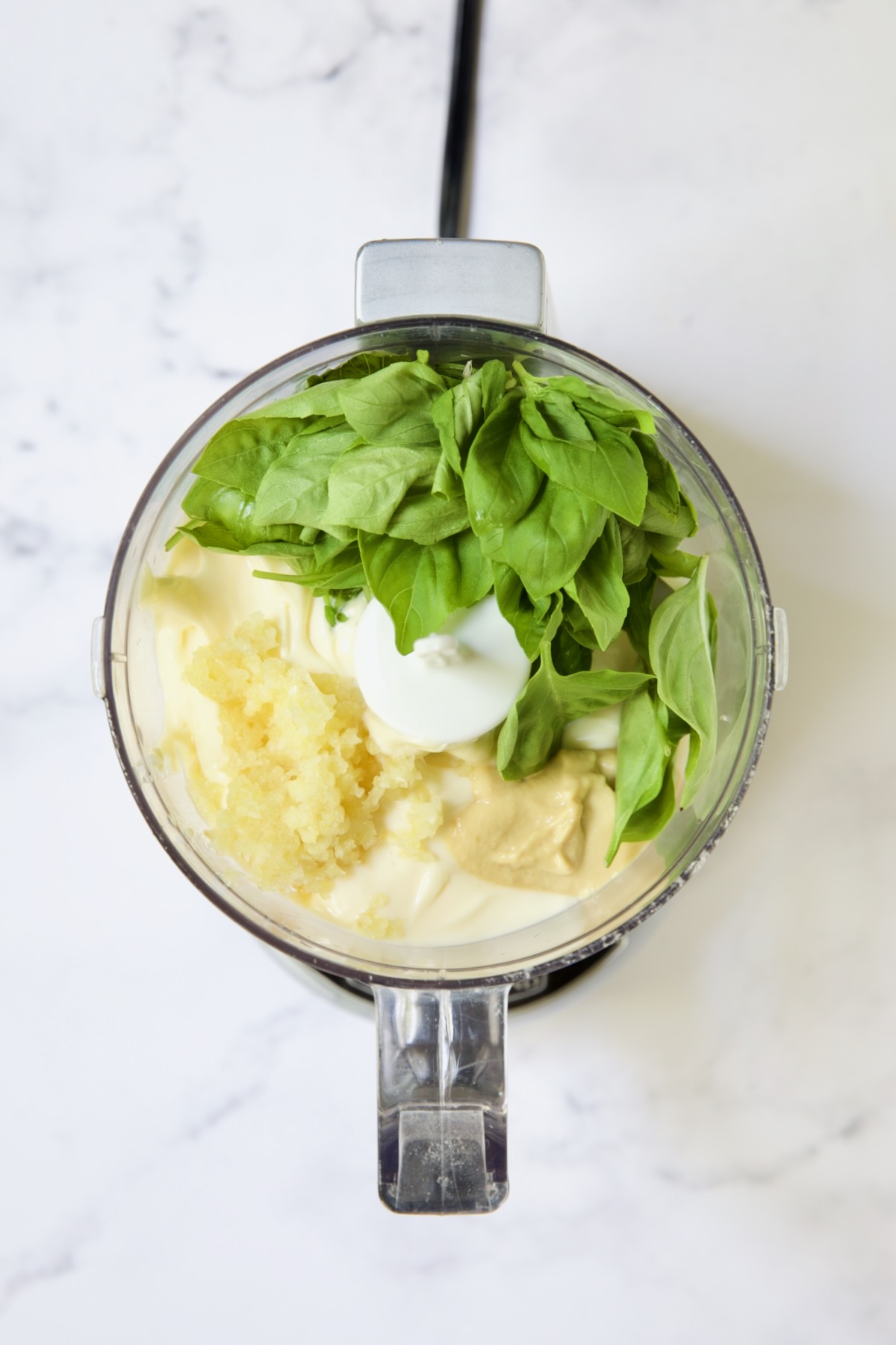 Ingredients for Garlic Basil Aioli in mini food processor.