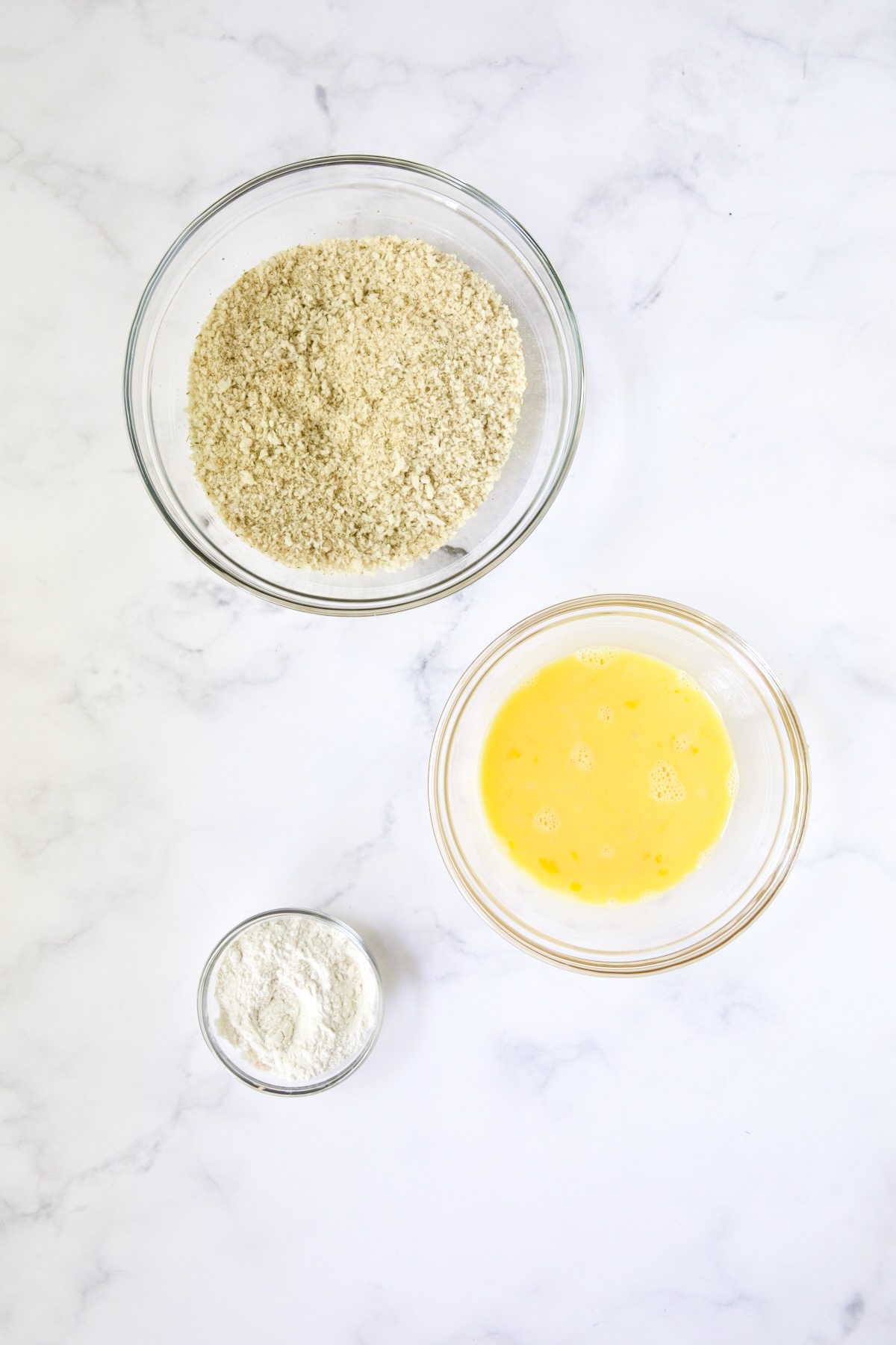 Three glass bowls: One consisting of breadcrumb blend, beaten eggs and all-purpose flour.