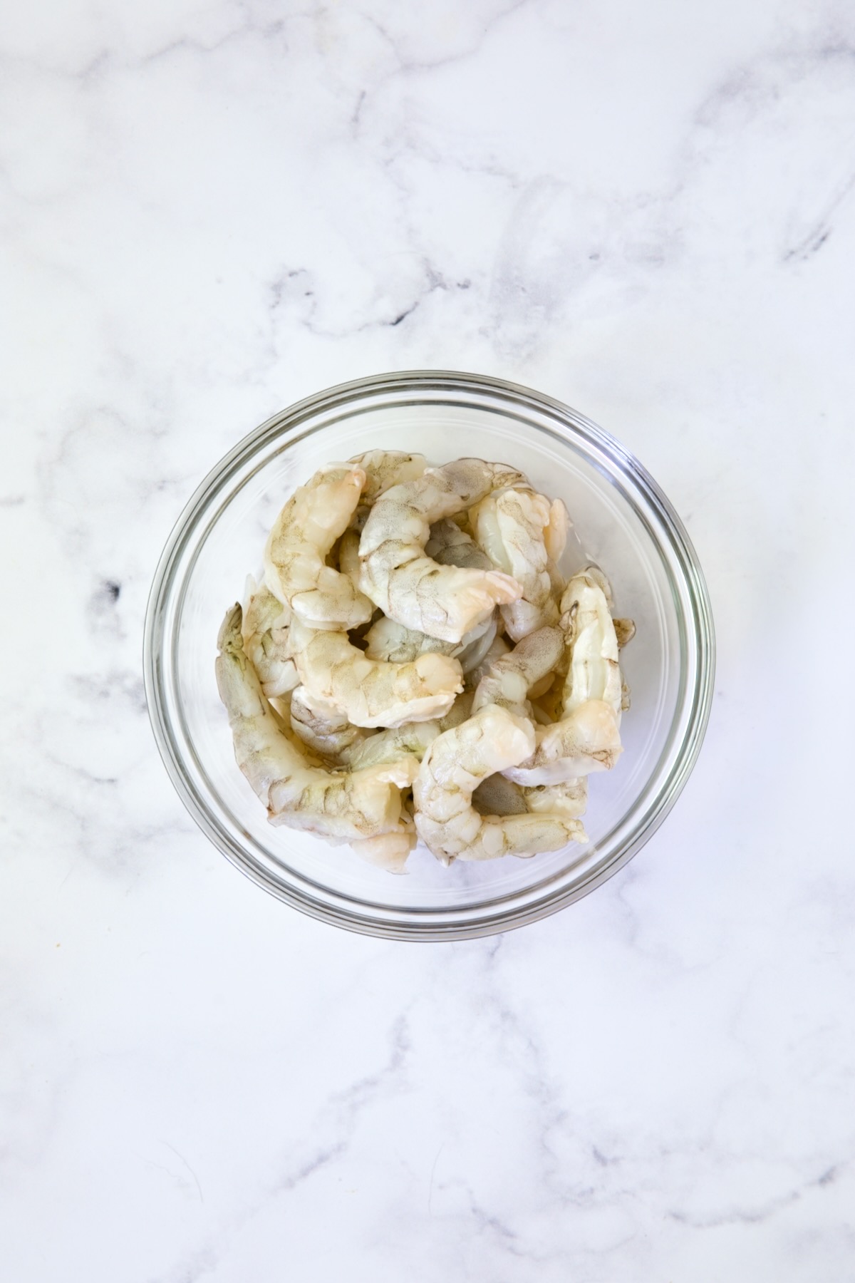 Uncooked shrimp in glass bowl.