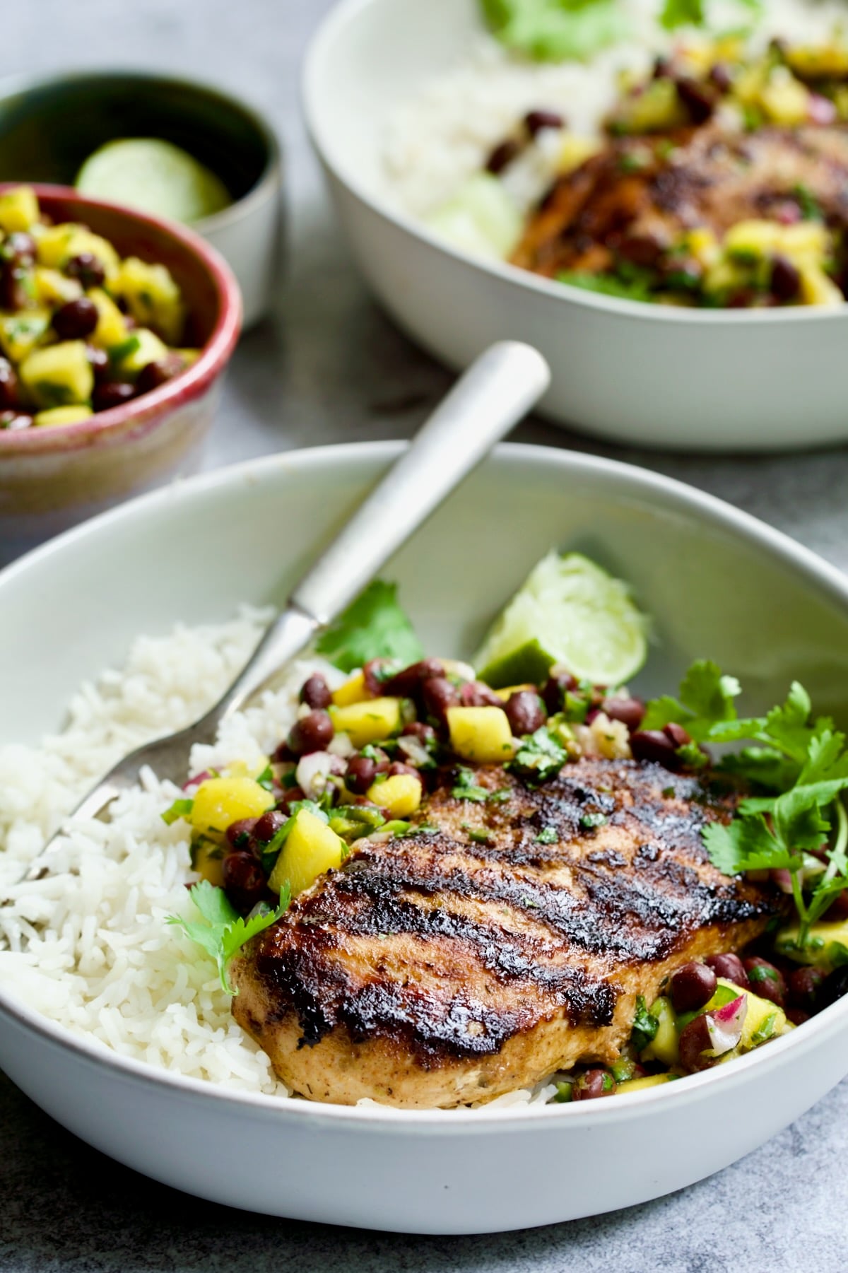 Caribbean Jerk Chicken with Mango Black Bean Salsa with white rice in white bowl.