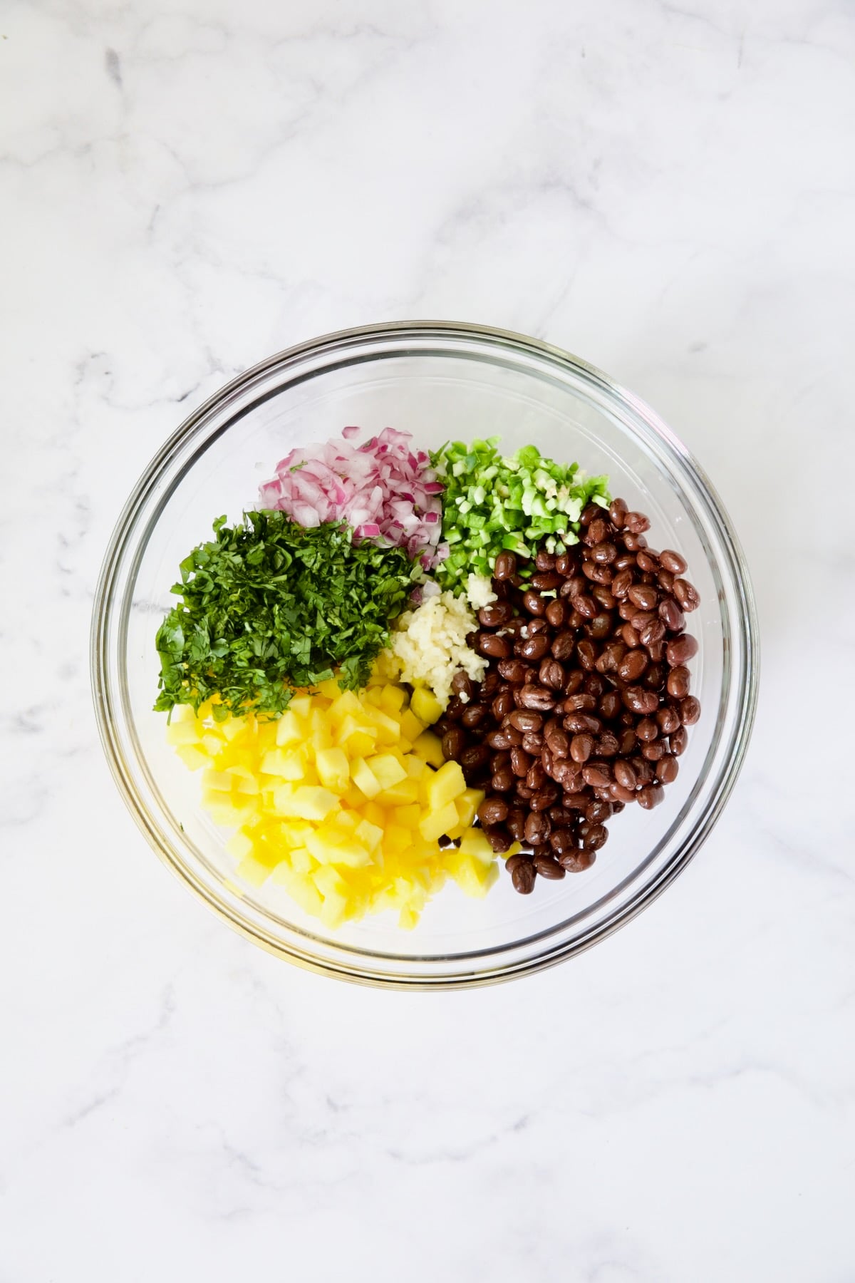 Ingredients for Black Bean Mango Salsa in glass bowl before being stirred.