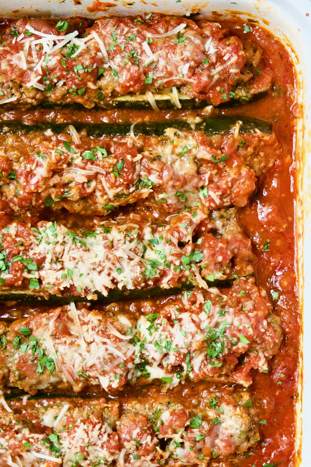 Close-up of five Meat-Stuffed Zucchini with Tomato Sauce.
