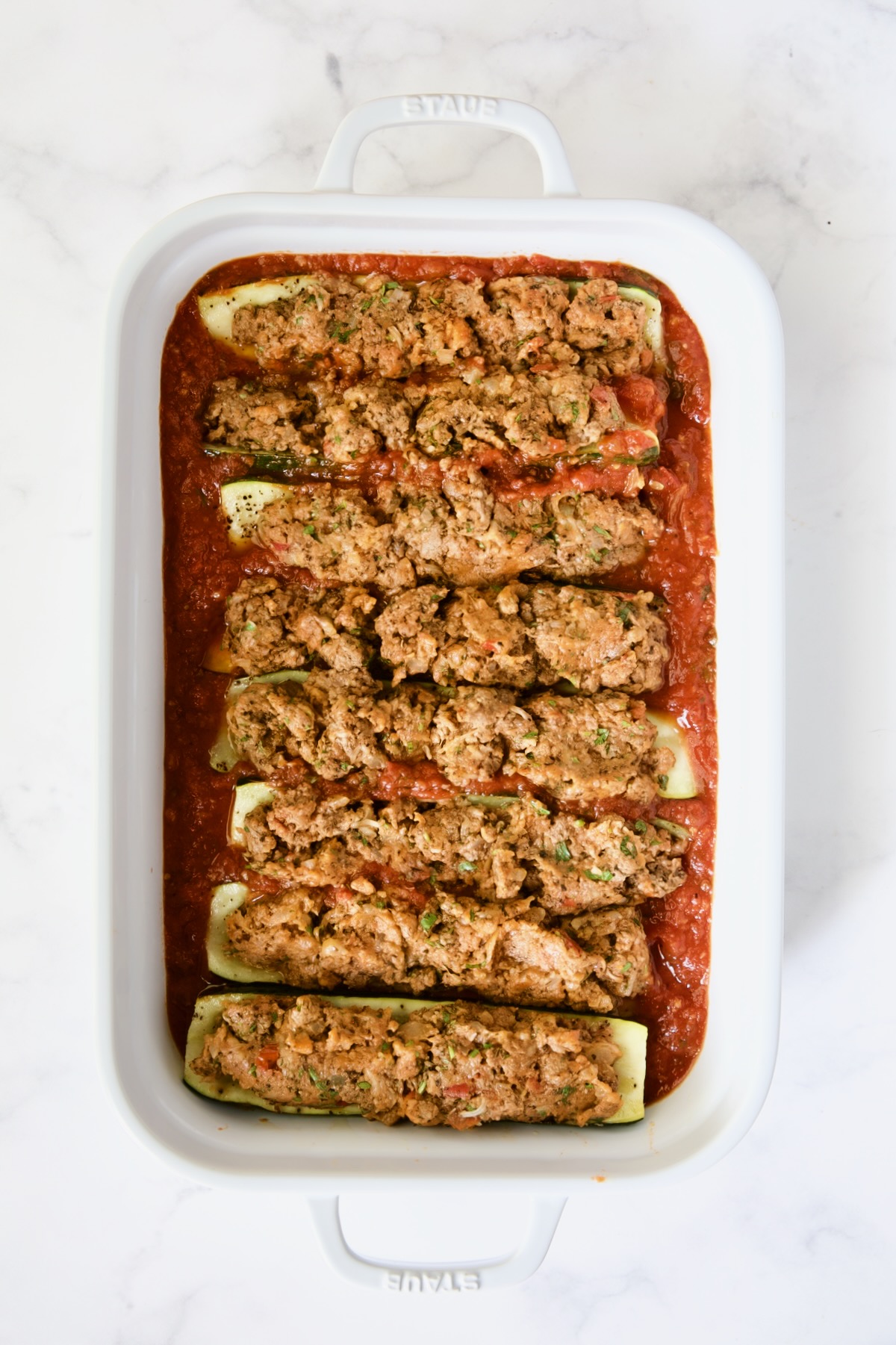 Meat-stuffed zucchini before tomato sauce is spooned over it.