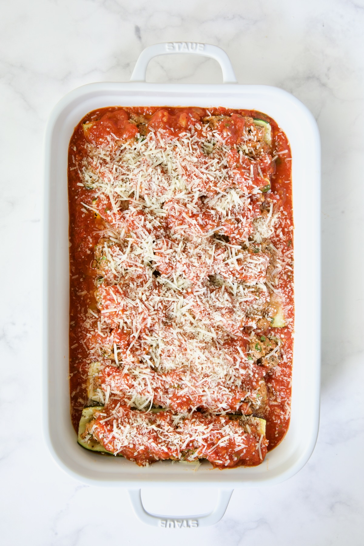 Unbaked pan of Meat-Stuffed Zucchini with Tomato Sauce.
