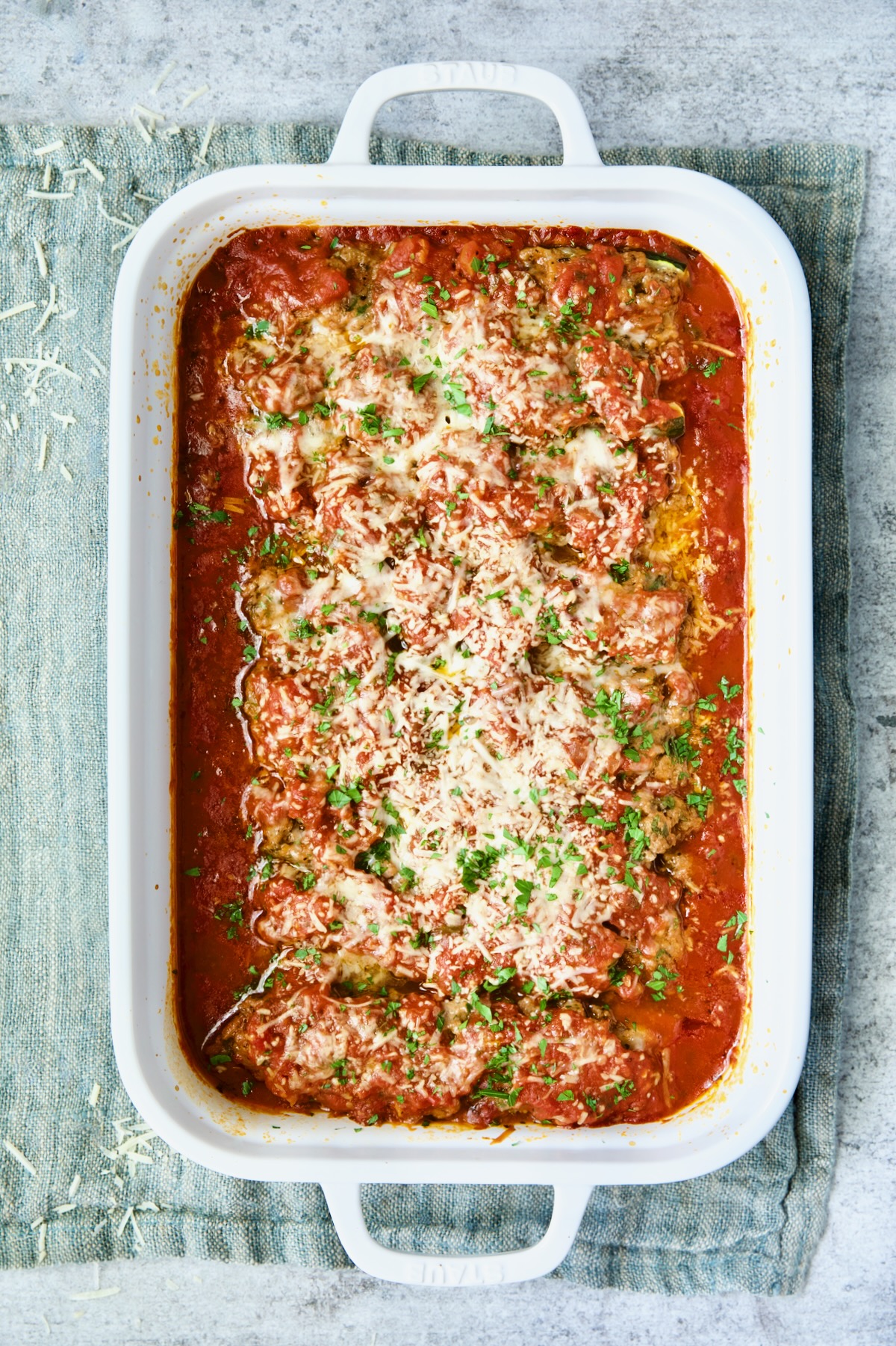 Baked Meat-Stuffed Zucchini with Tomato Sauce fresh out of the oven on blue napkin.