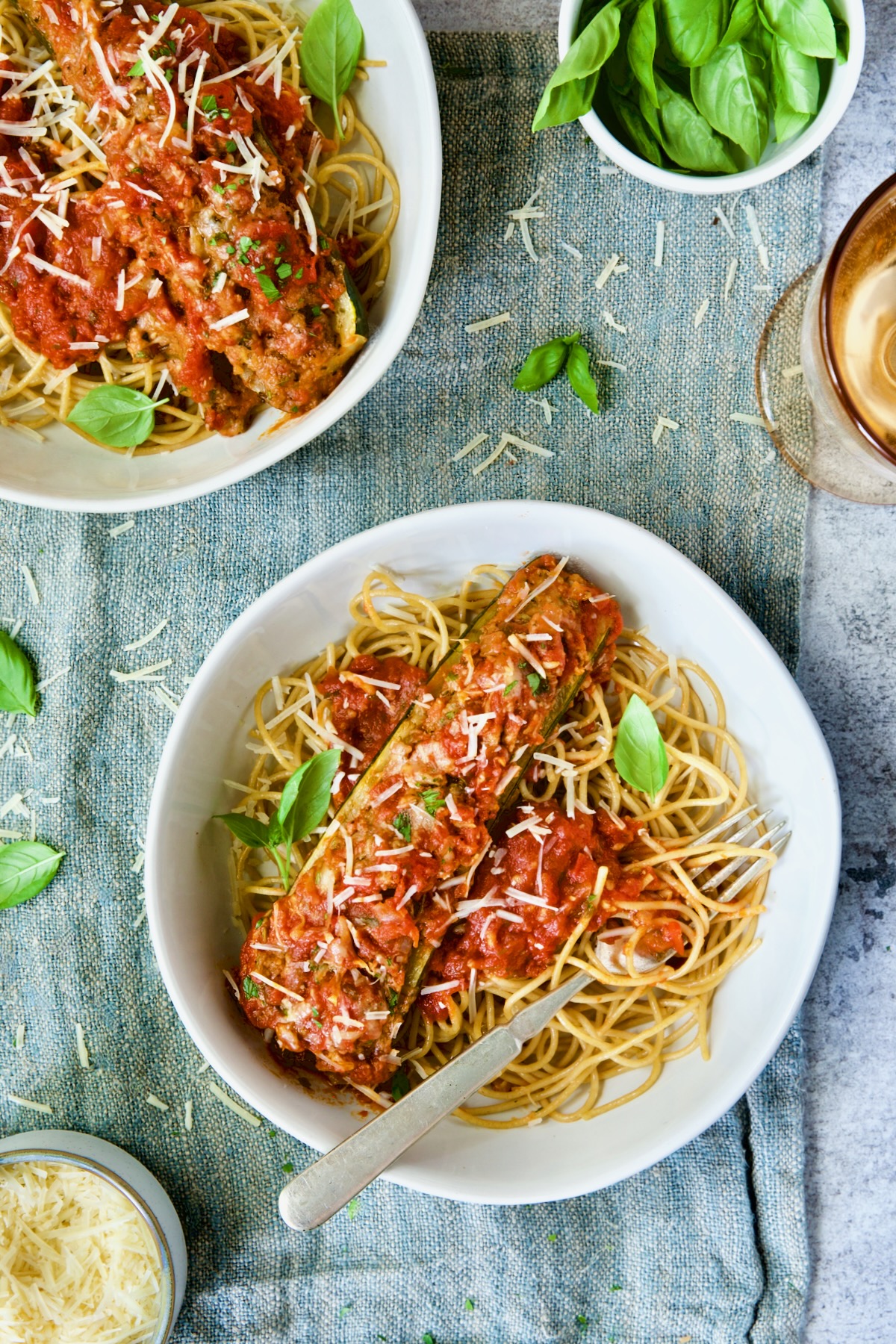 Two bowls of Meat-Stuffed Zucchini with Tomato Sauce on blue napkin.