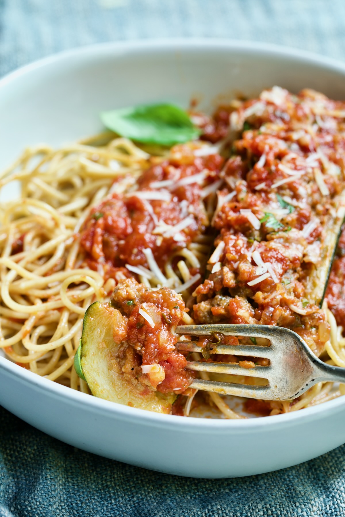 Meat-Stuffed Zucchini with Tomato Sauce over spaghetti with a forkful of zucchini with meat.