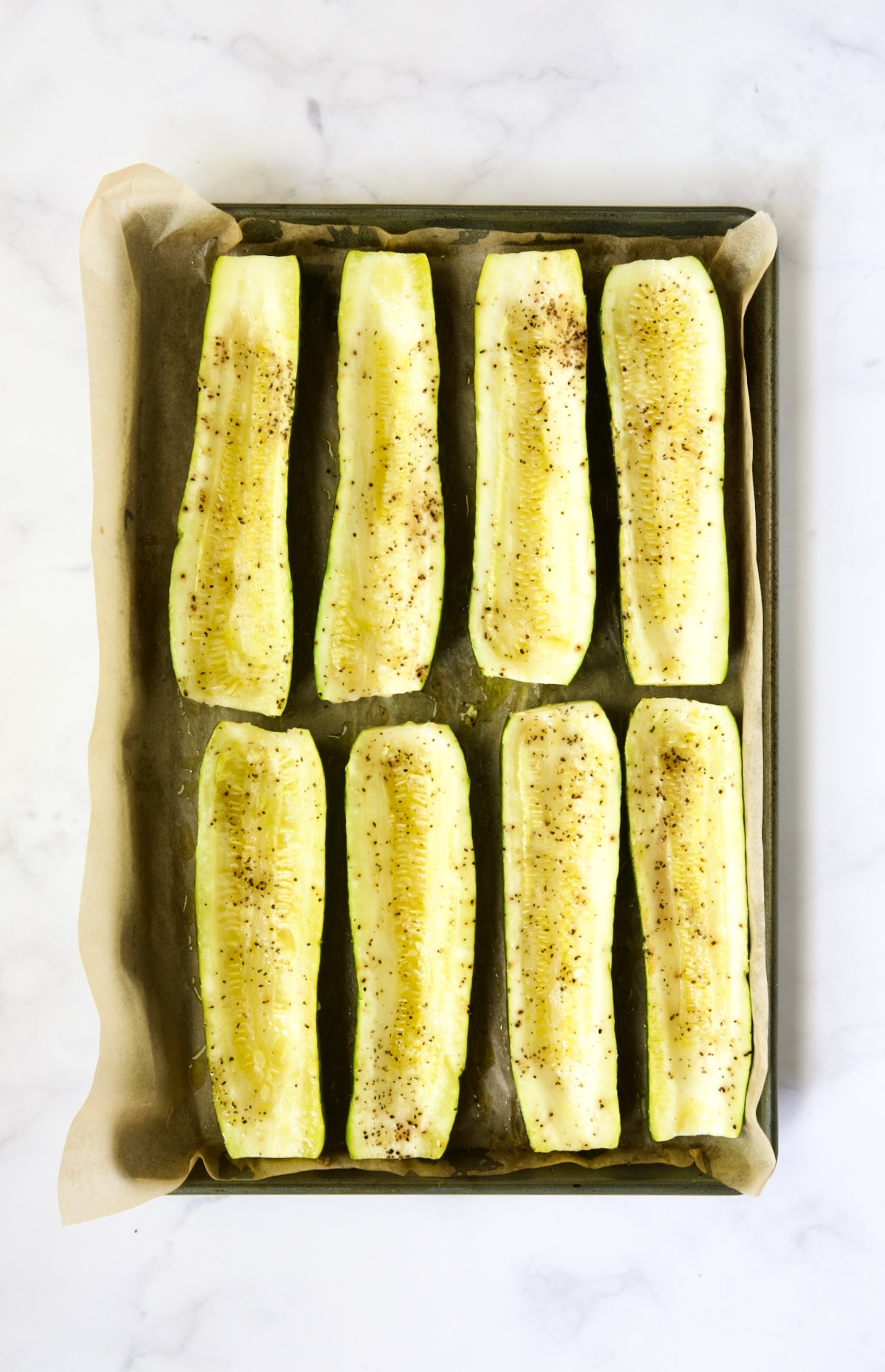 Roasted zucchini halves on parchment paper-lined rimmed baking sheet.