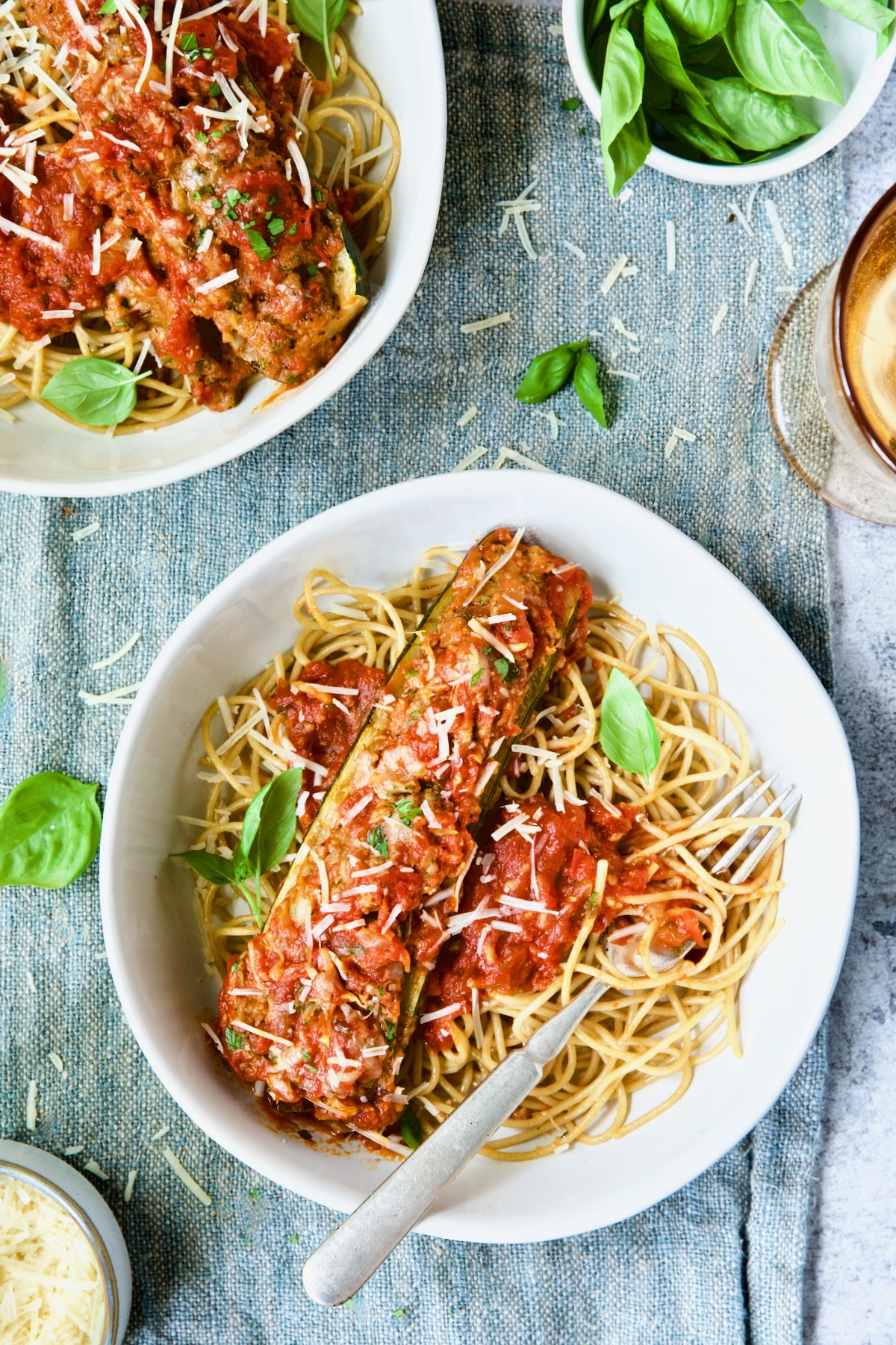 Two bowls of Meat-Stuffed Zucchini with Tomato Sauce on blue napkin.