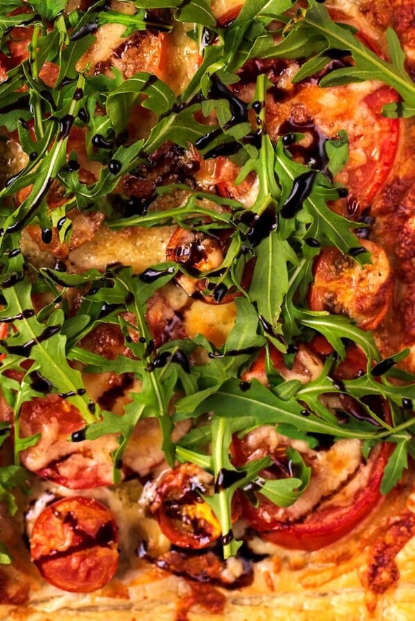 Tomato Puff Pastry Tart topped with arugula and drizzled with balsamic vinegar.