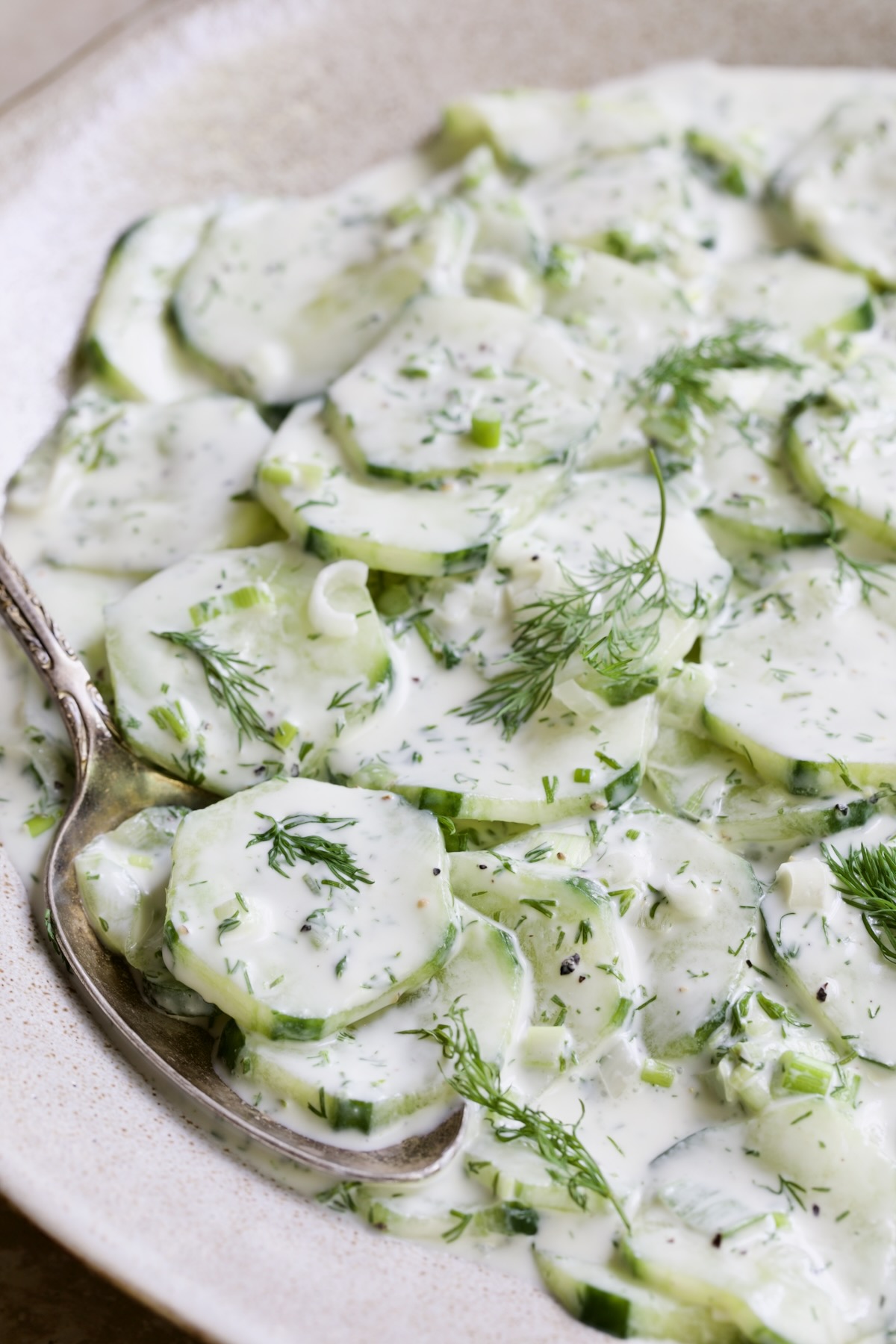 Yogurt Ranch Cucumber Salad in serving bowl with spoon lifting some out.