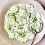 Creamy Cucumber Salad with Yogurt in serving bowl with antique serving spoon.