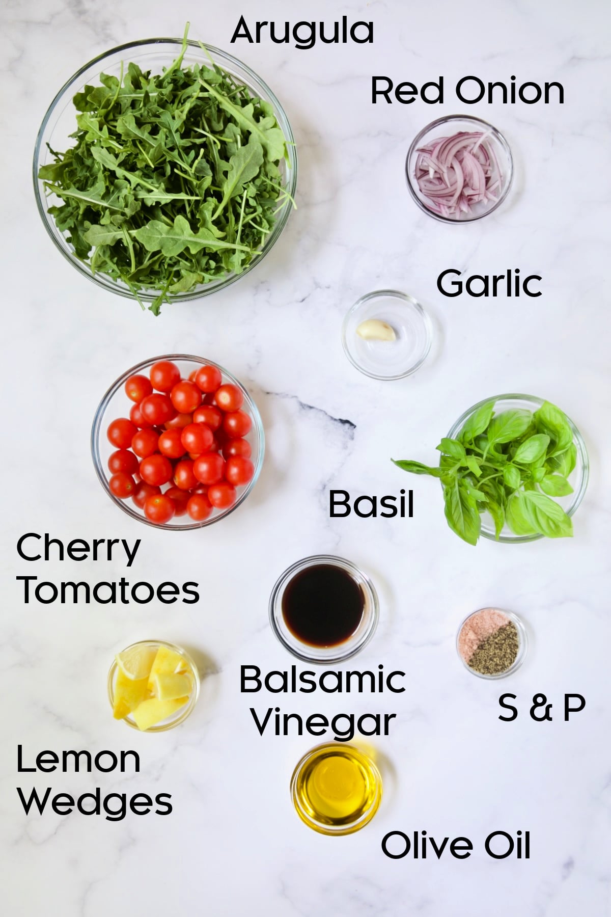 Ingredients for Arugula and Cherry Tomato Salad in glass bowls.
