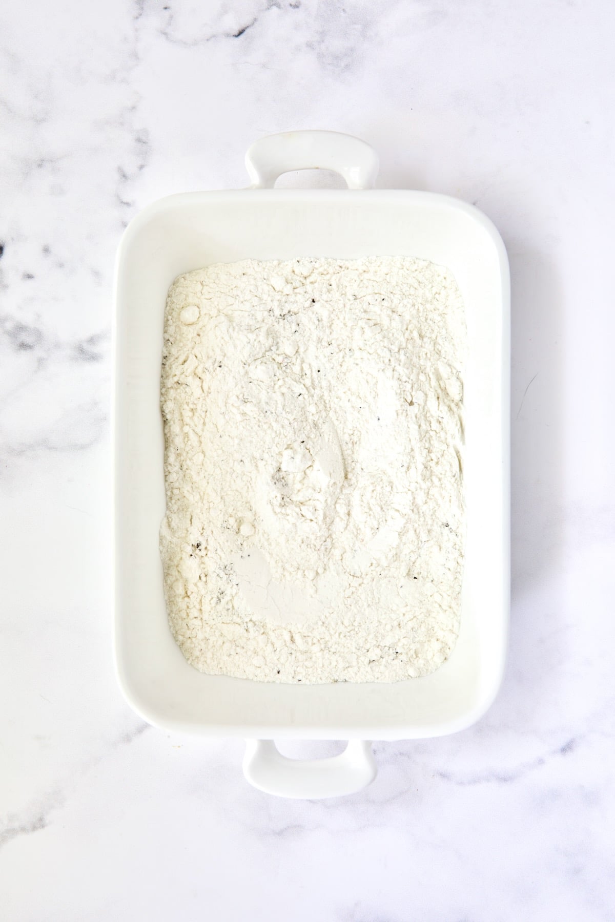Seasoned flour in white dish.