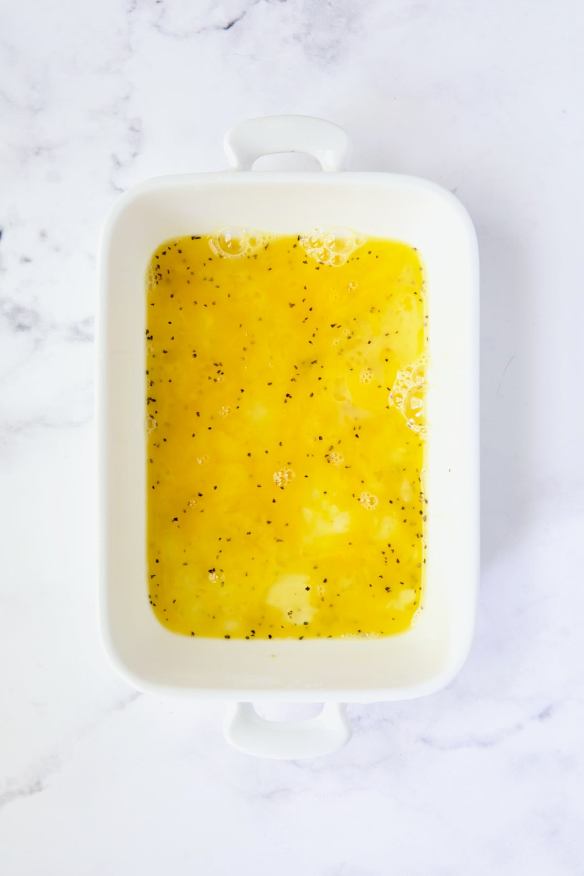 Beaten egg mixture in white dish.