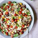 Mediterranean Chopped Salad with Chickpeas in blue serving bowl garnished with fresh parsley.