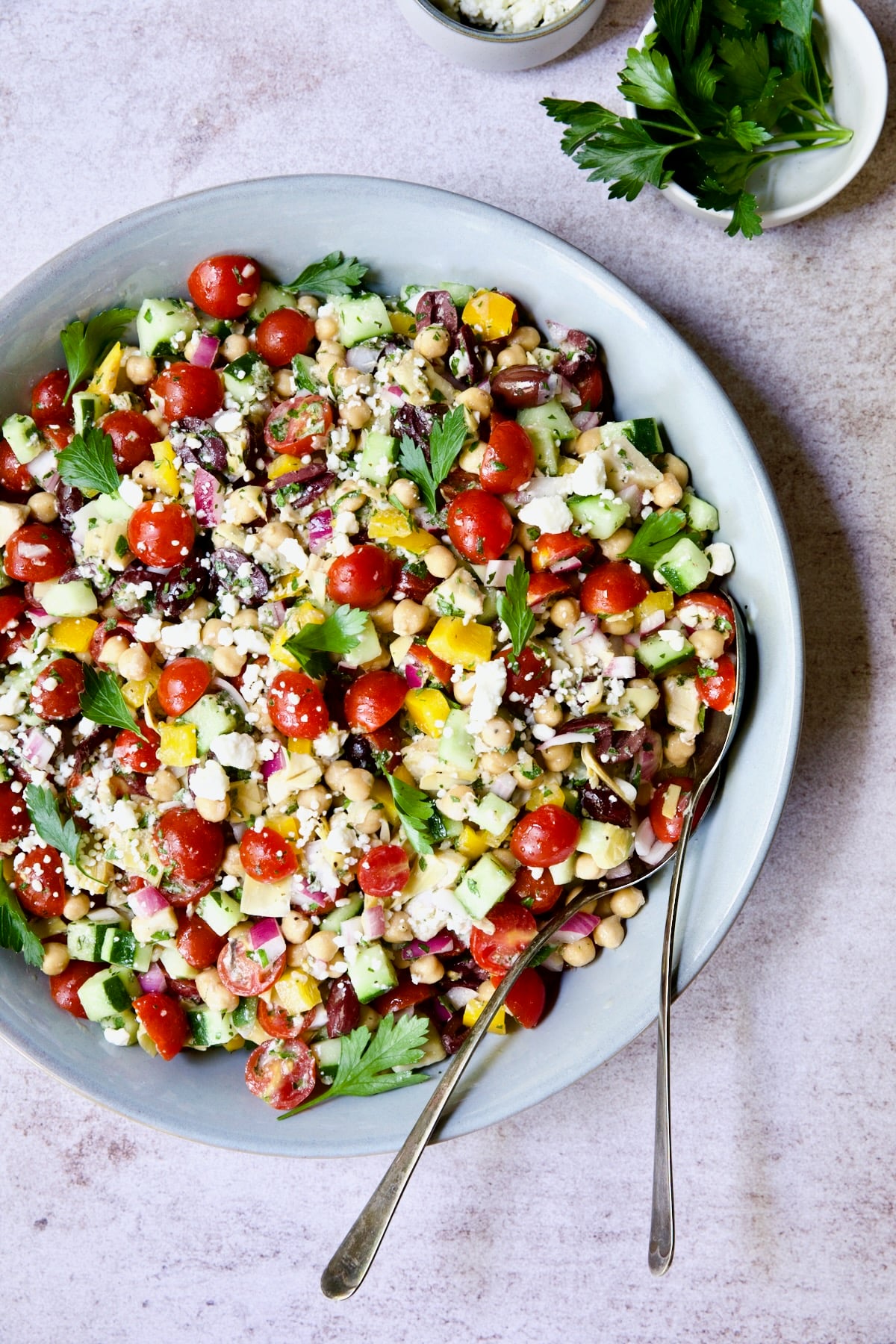 Mediterranean Chopped Salad with Chickpeas in blue serving bowl garnished with fresh parsley.