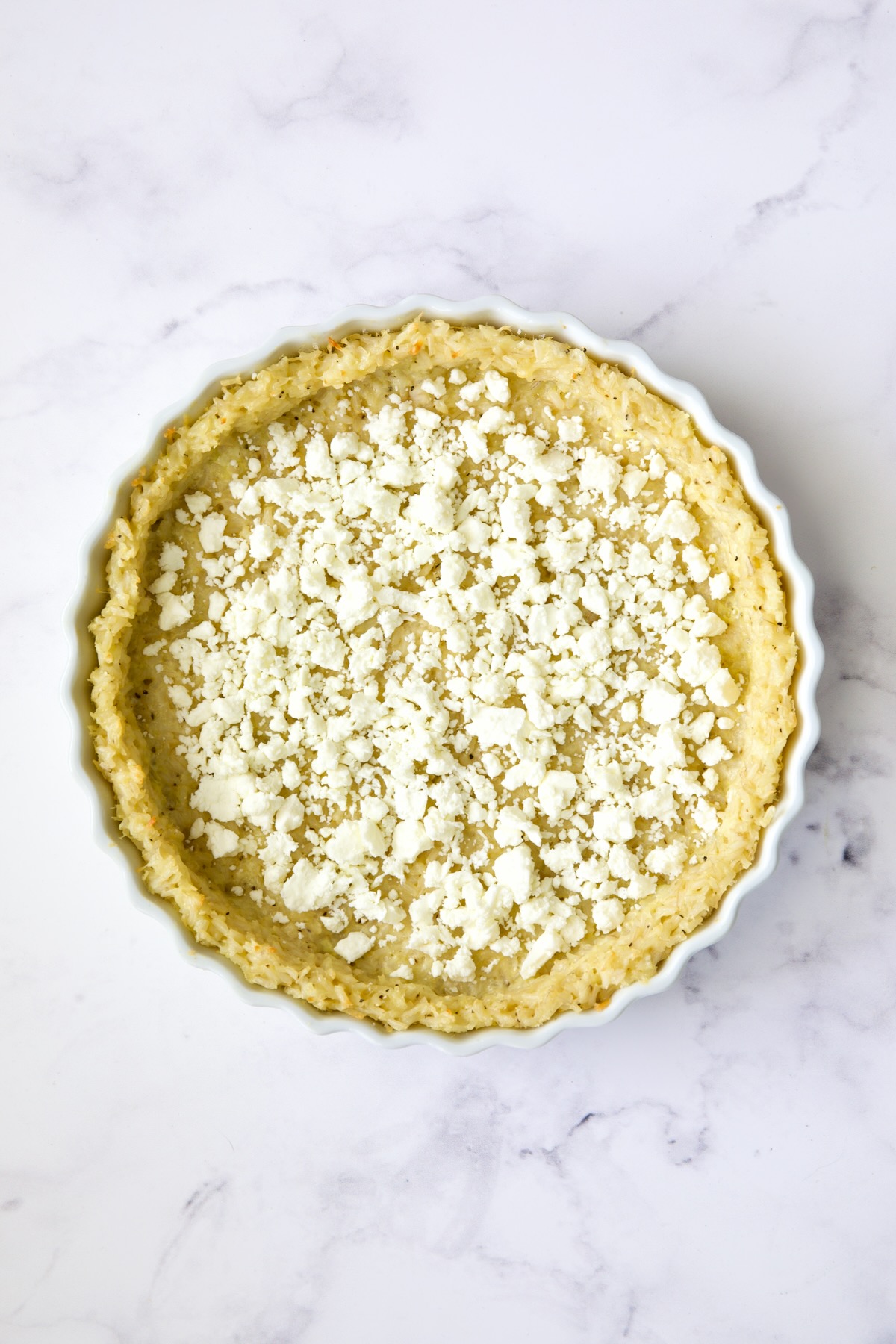 Feta cheese scattered over brown rice crust.