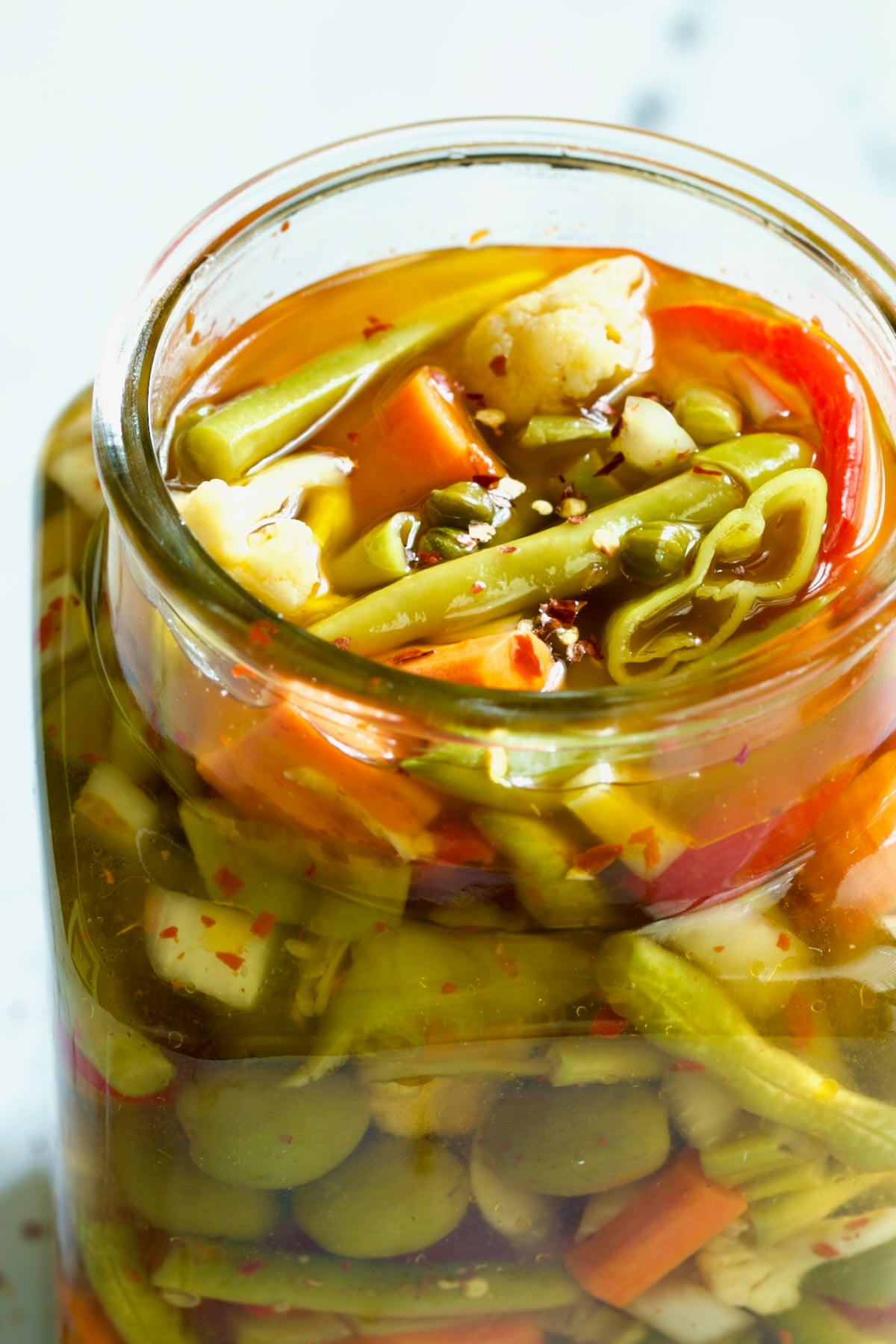 Pickled vegetables in glass jar with brine.