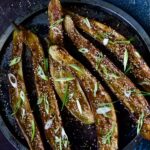 Six Miso-Glazed Eggplant halves on metal tray garnished with sesame seeds and scallions.
