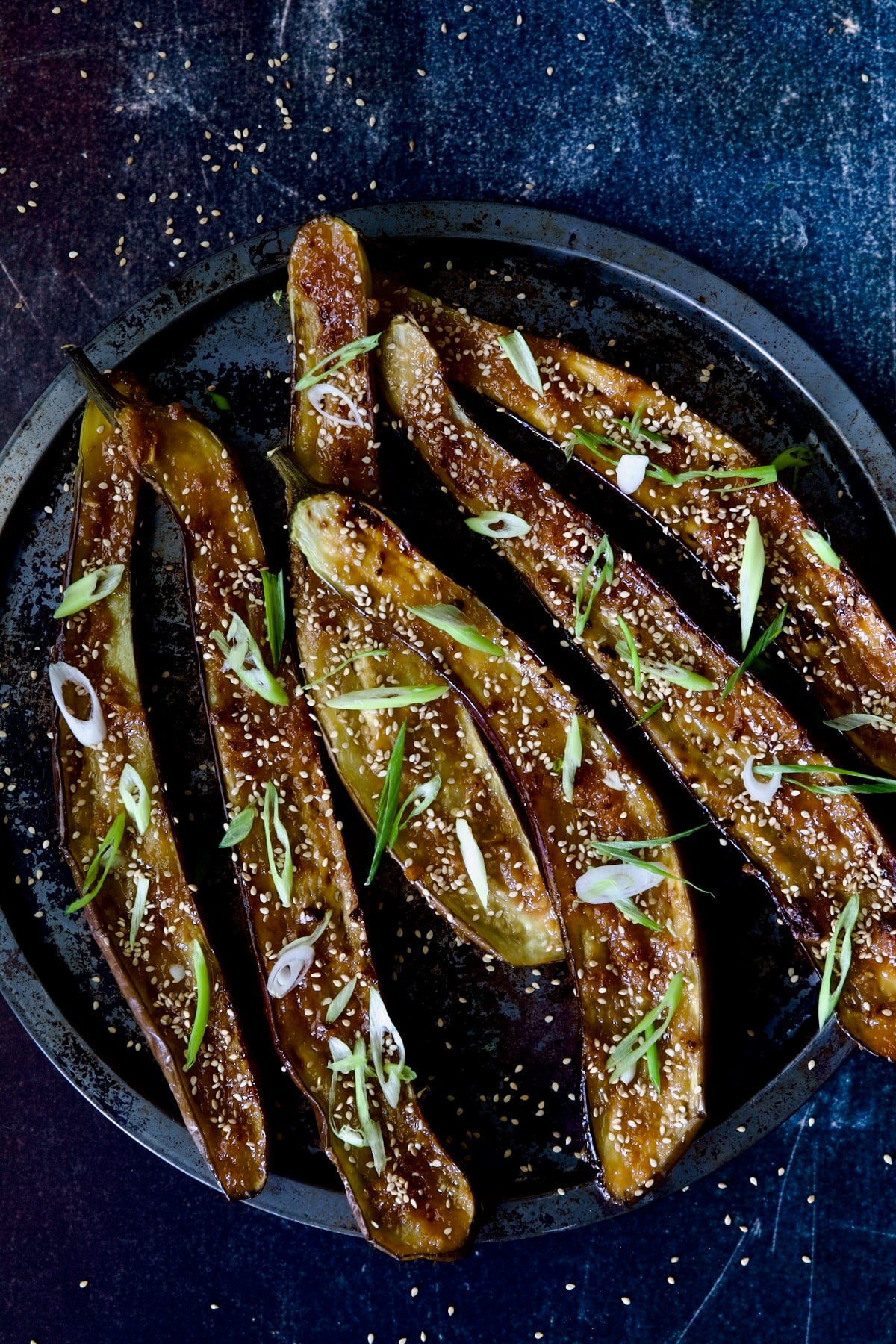 Six Miso-Glazed Eggplant halves on metal tray garnished with sesame seeds and scallions.