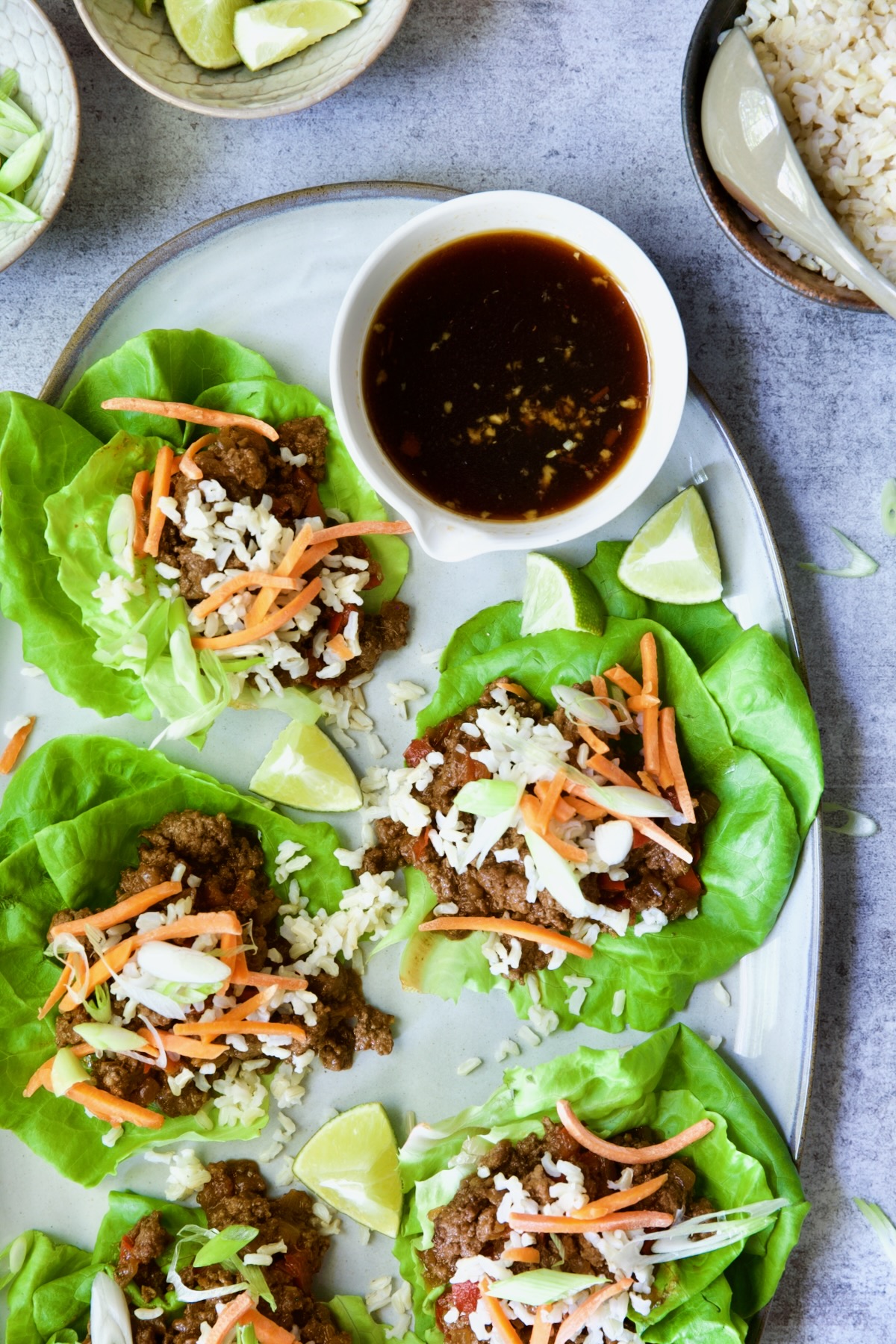 Beef Lettuce Wraps Recipe with Lime Ginger Dipping Sauce on gray platter.