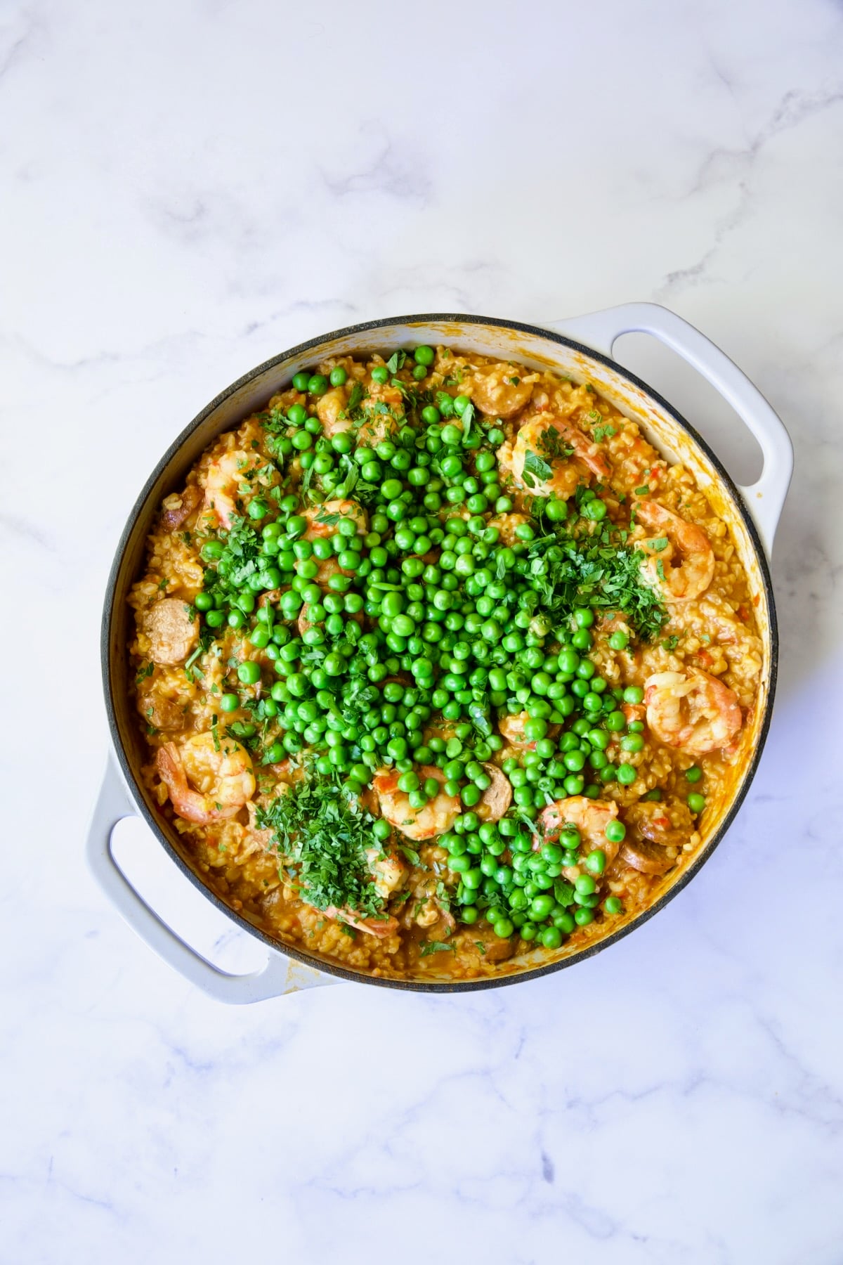 Process shot of paella with peas added.