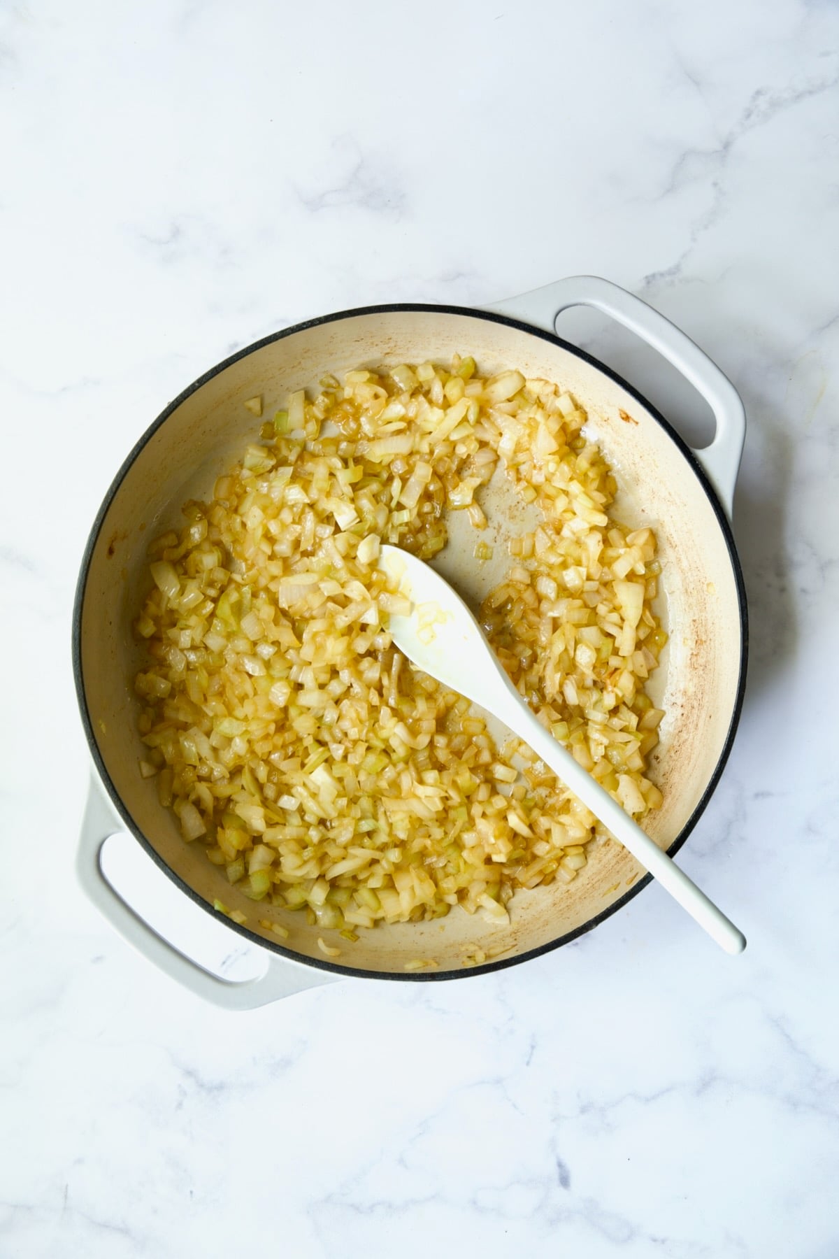 Cooked onions in white enamel cast iron skillet.