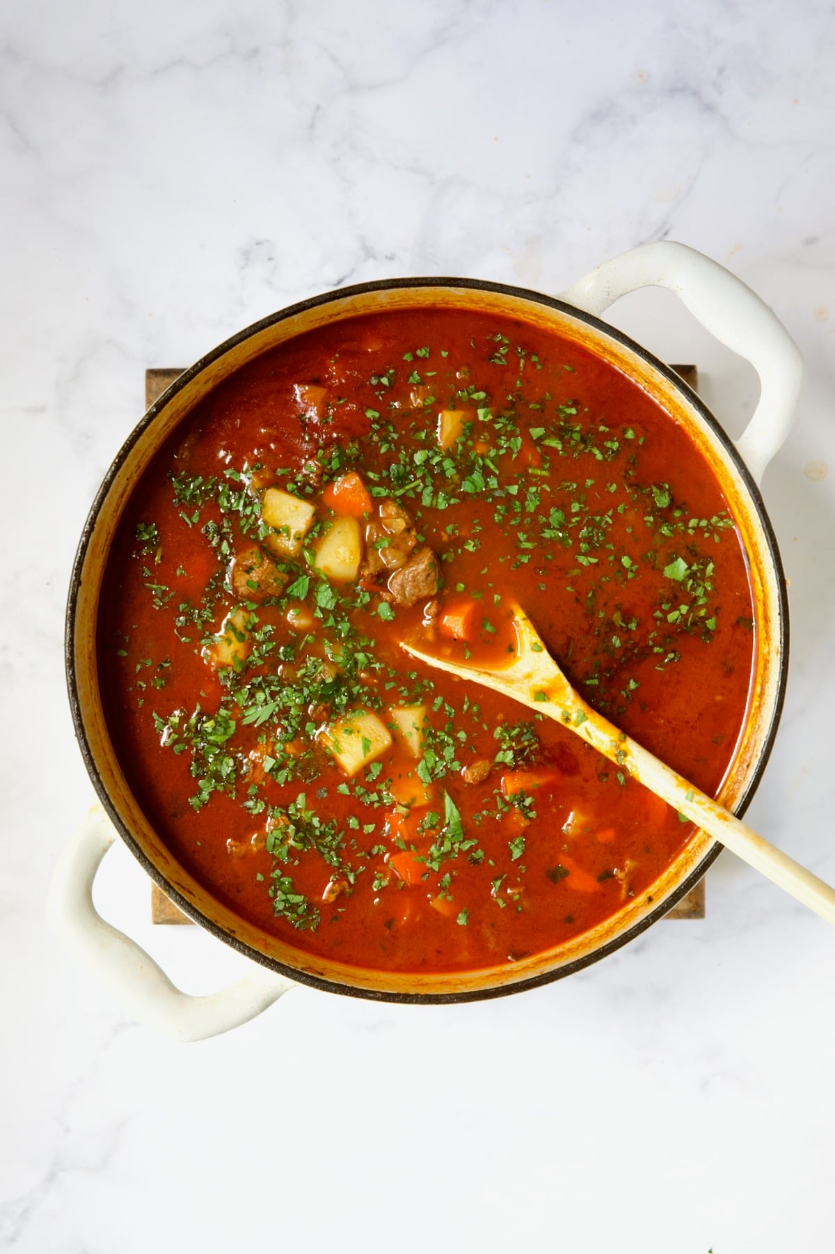 Finished goulash process shot in white Dutch oven.