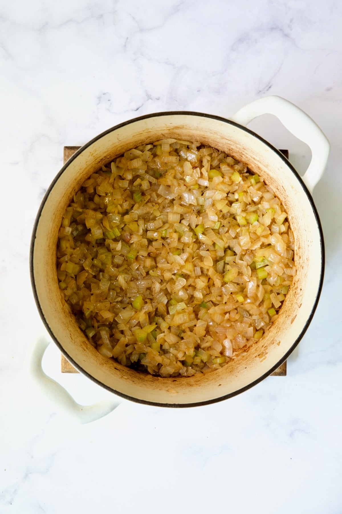 Cooked onions and celery in white Dutch oven.