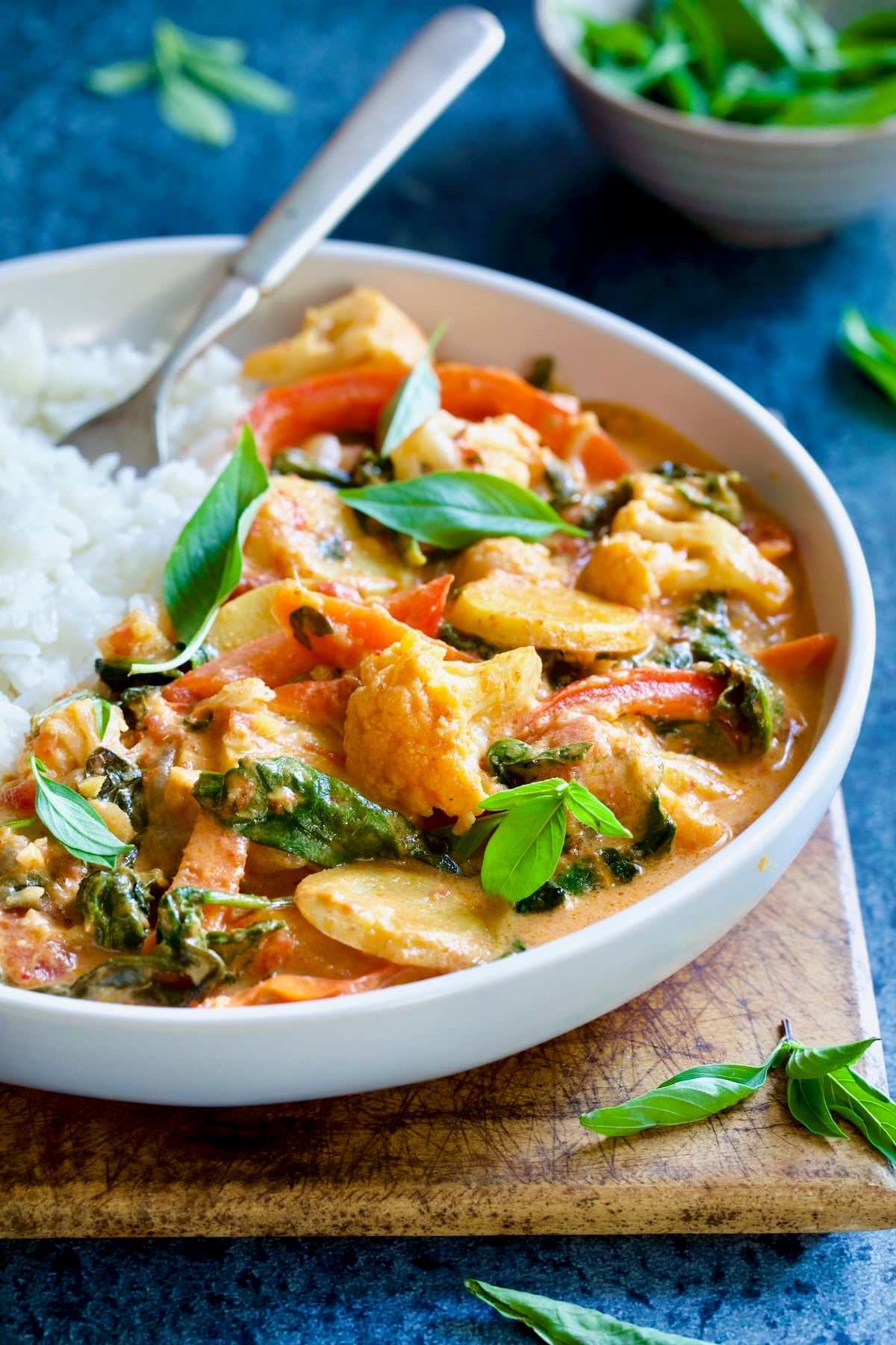 Vegan Thai Red Curry in white bowl garnished with fresh basil.