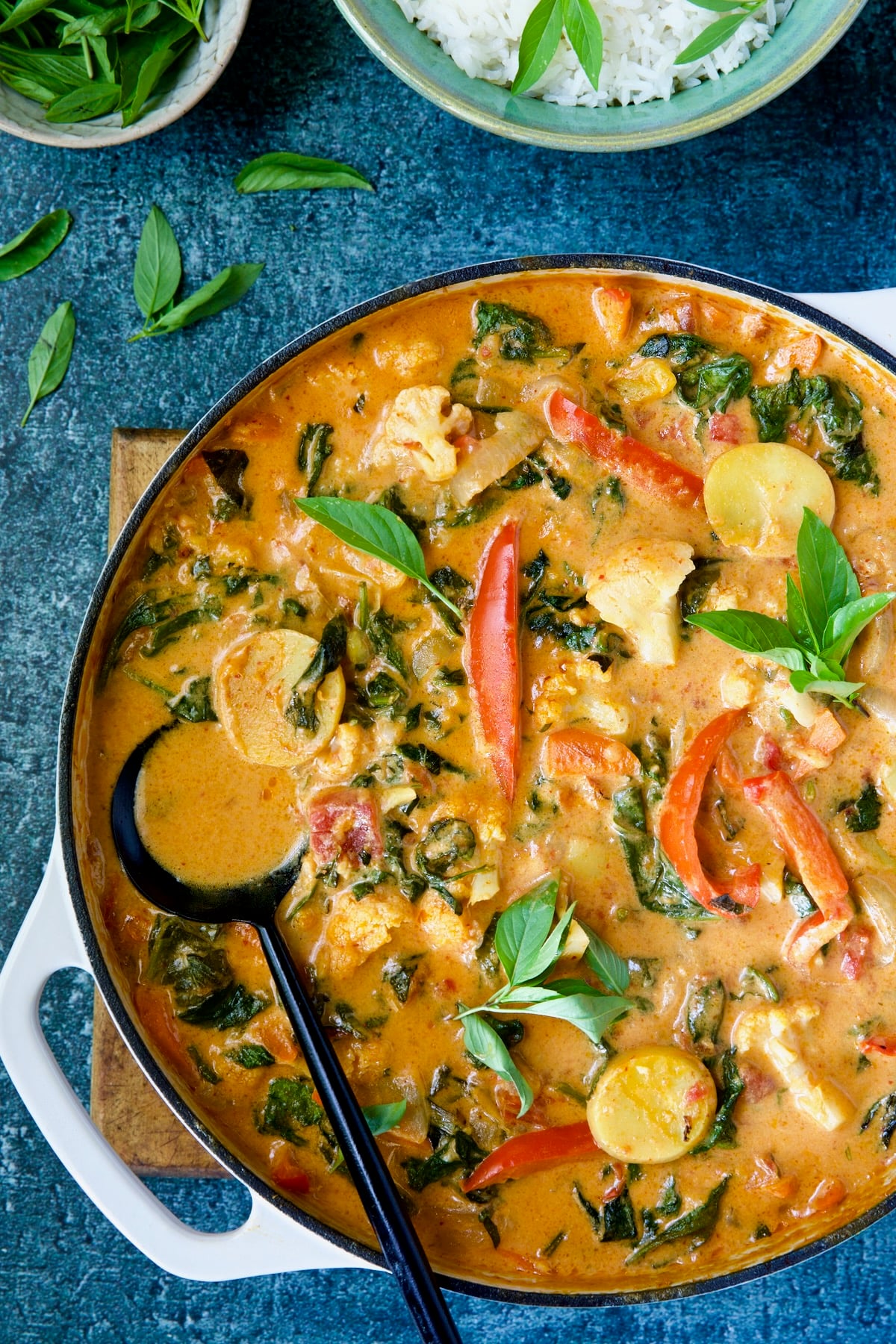 Vegan Thai Red Curry in white enamel cast iron skillet with black serving spoon.