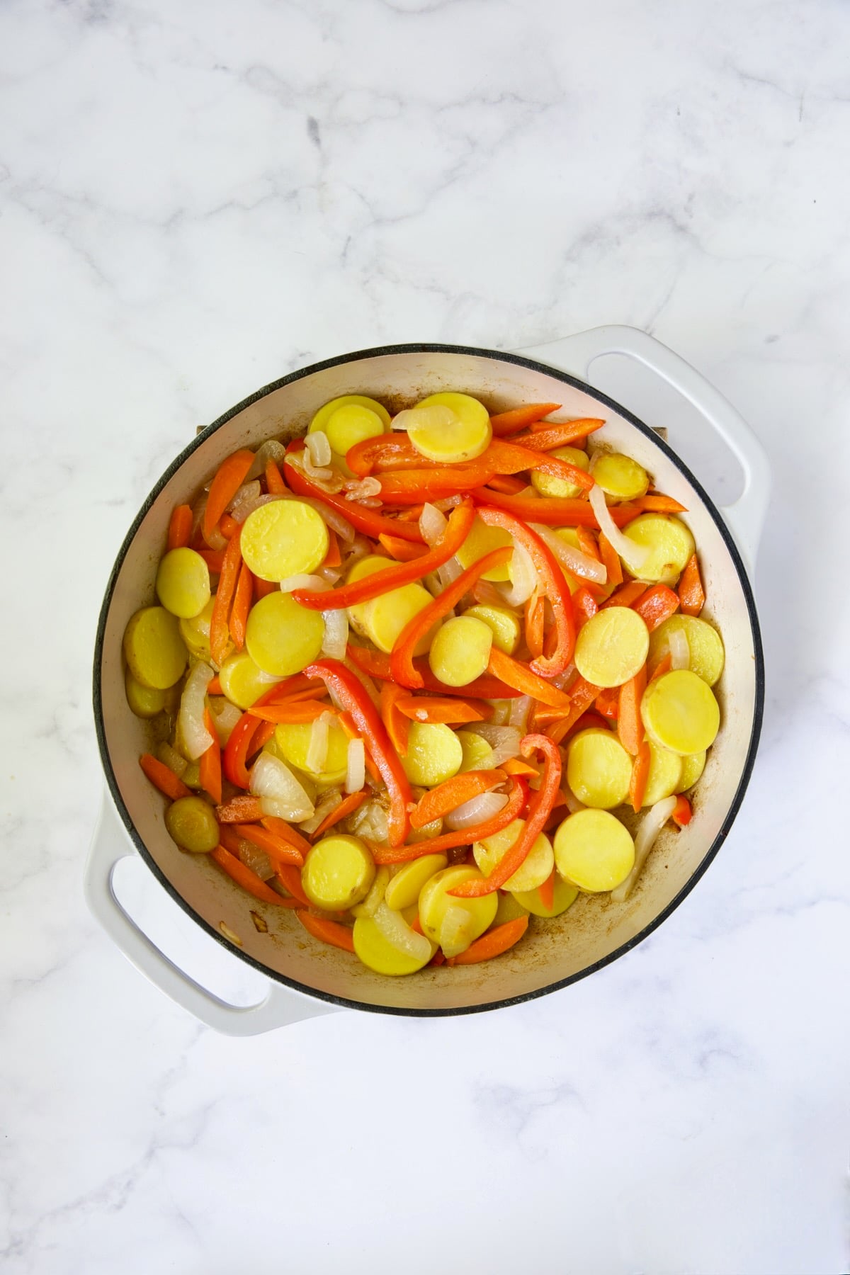 Process shot of onions, red bell pepper and potatoes.