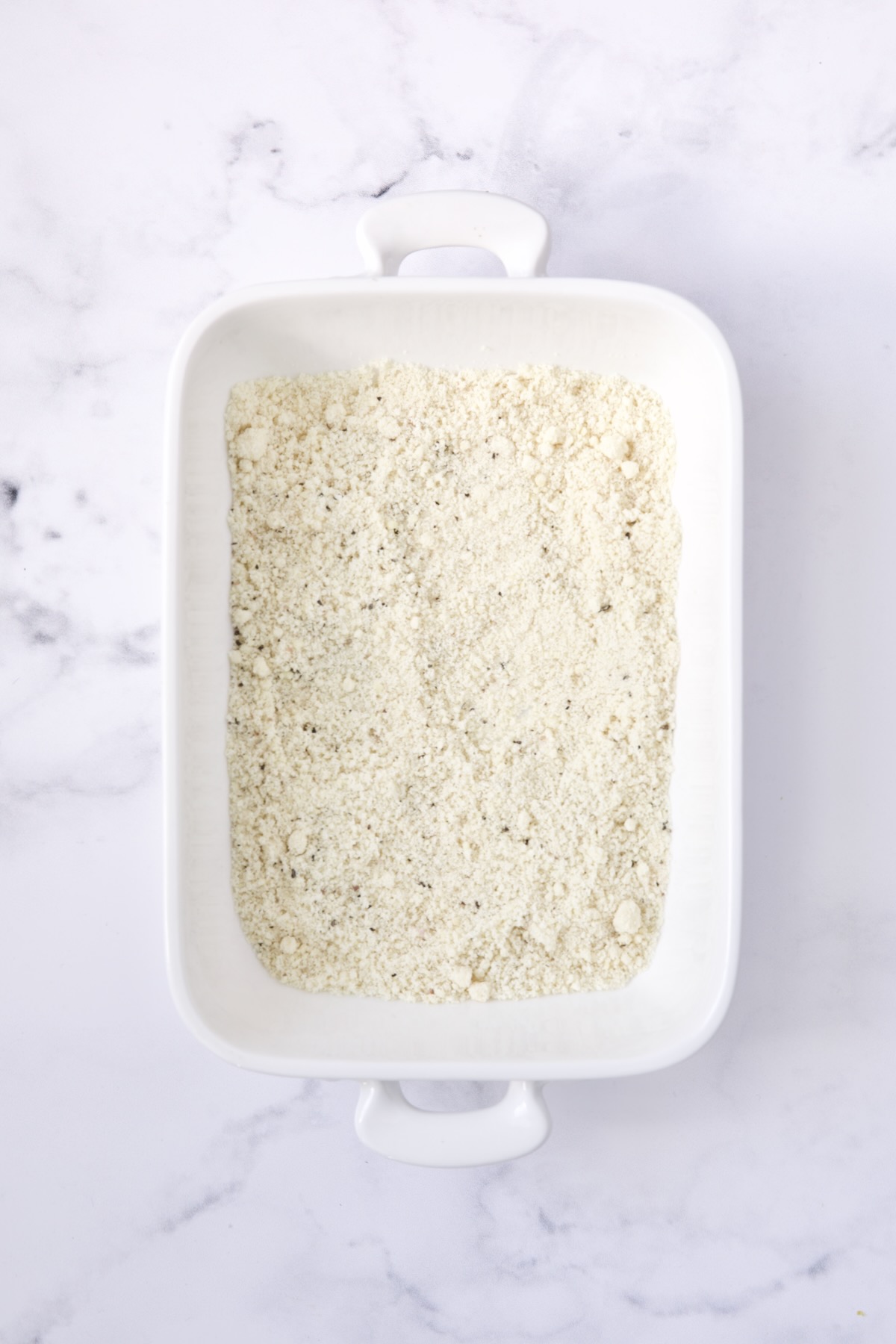 Seasoned almond flour in white rectangular baking pan.