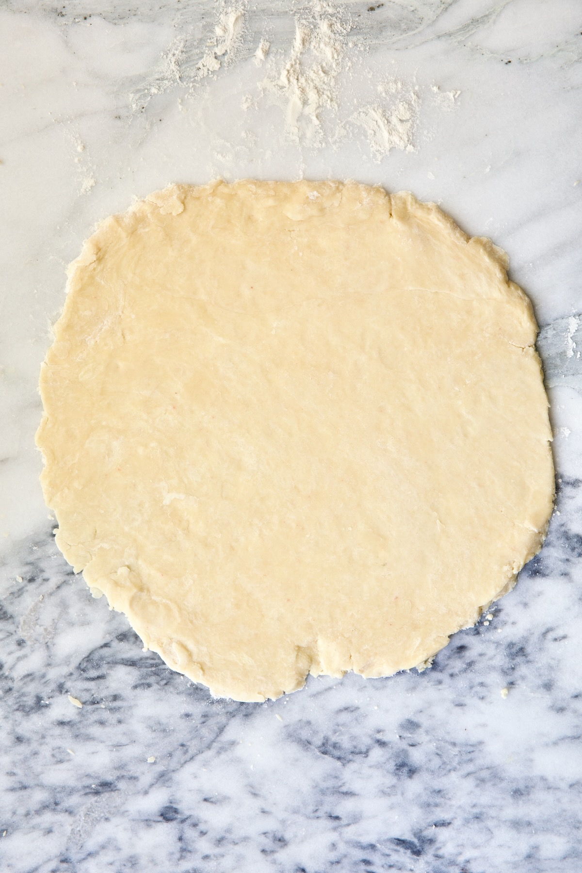 Galette dough on white marble pastry board.
