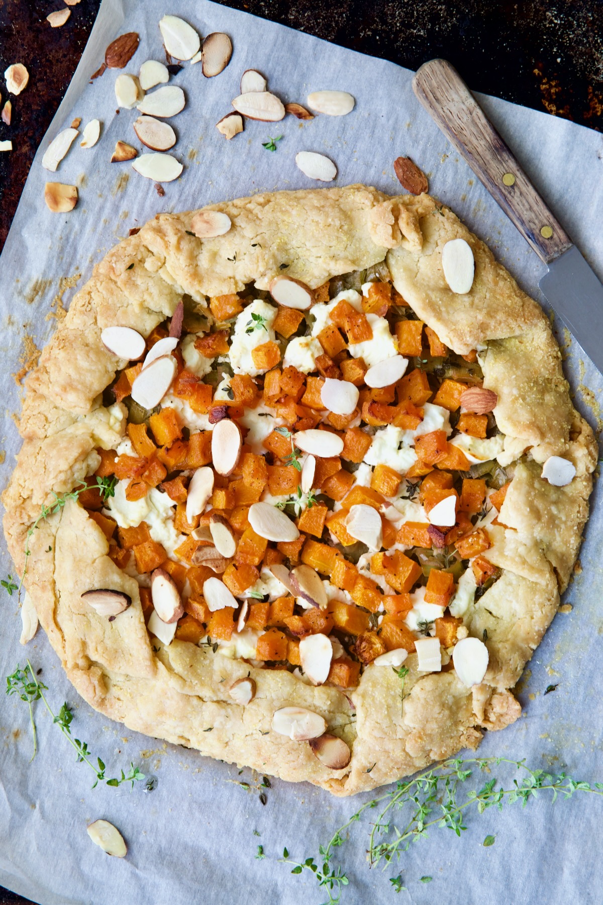 Baked Butternut Squash Leek and Goat Cheese Galette on white parchment paper.