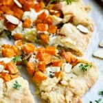 Wedge of Butternut Squash Leek and Goat Cheese Galette garnished with fresh thyme.