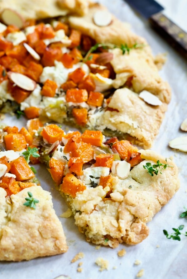 Wedge of Butternut Squash Leek and Goat Cheese Galette garnished with fresh thyme.