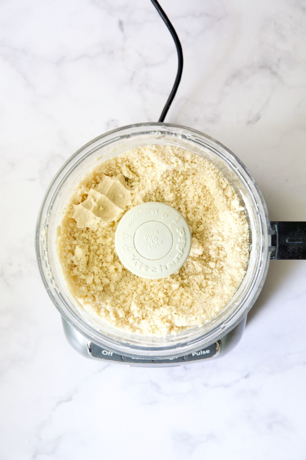 Ingredients for galette dough in food processor with some pinched together to show it will hold together.